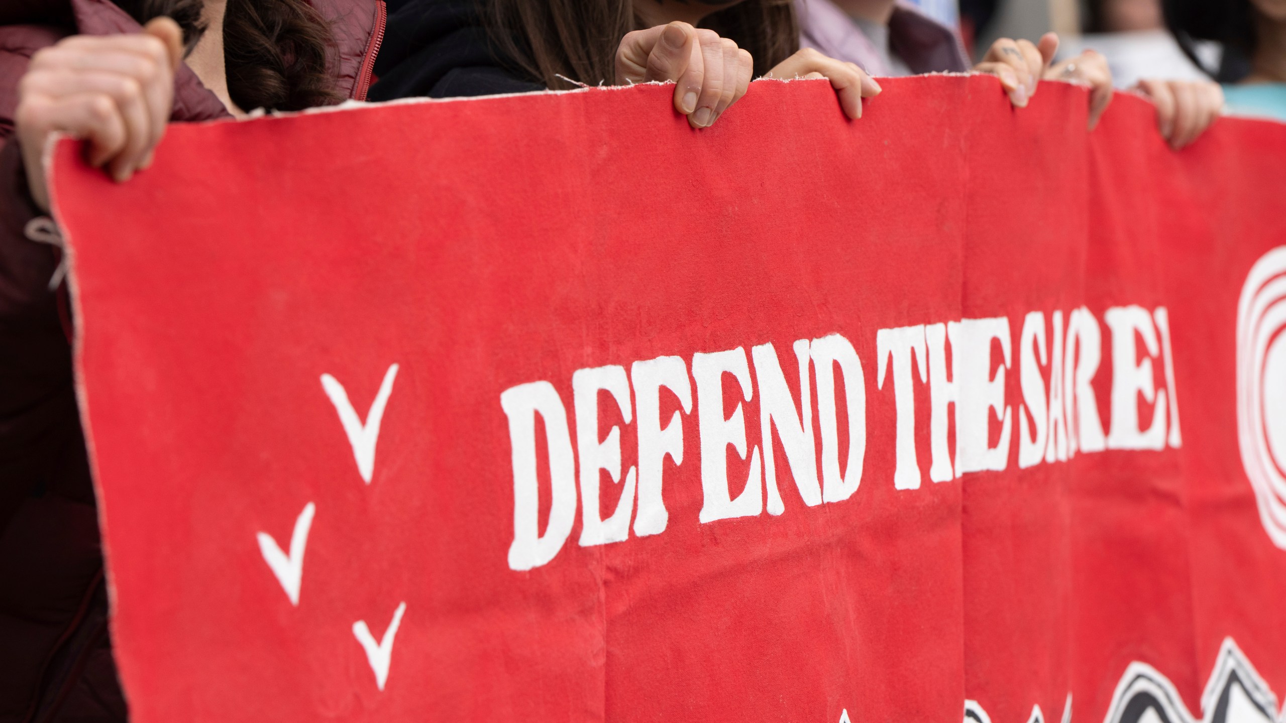 CORRECTS TO ANCHORAGE INSTEAD OF DEADHORSE - People hold a sign during a protest outside the annual Alaska Sustainable Energy Conference on Tuesday, June 3, 2025, in Anchorage, Alaska. (AP Photo/Jenny Kane)