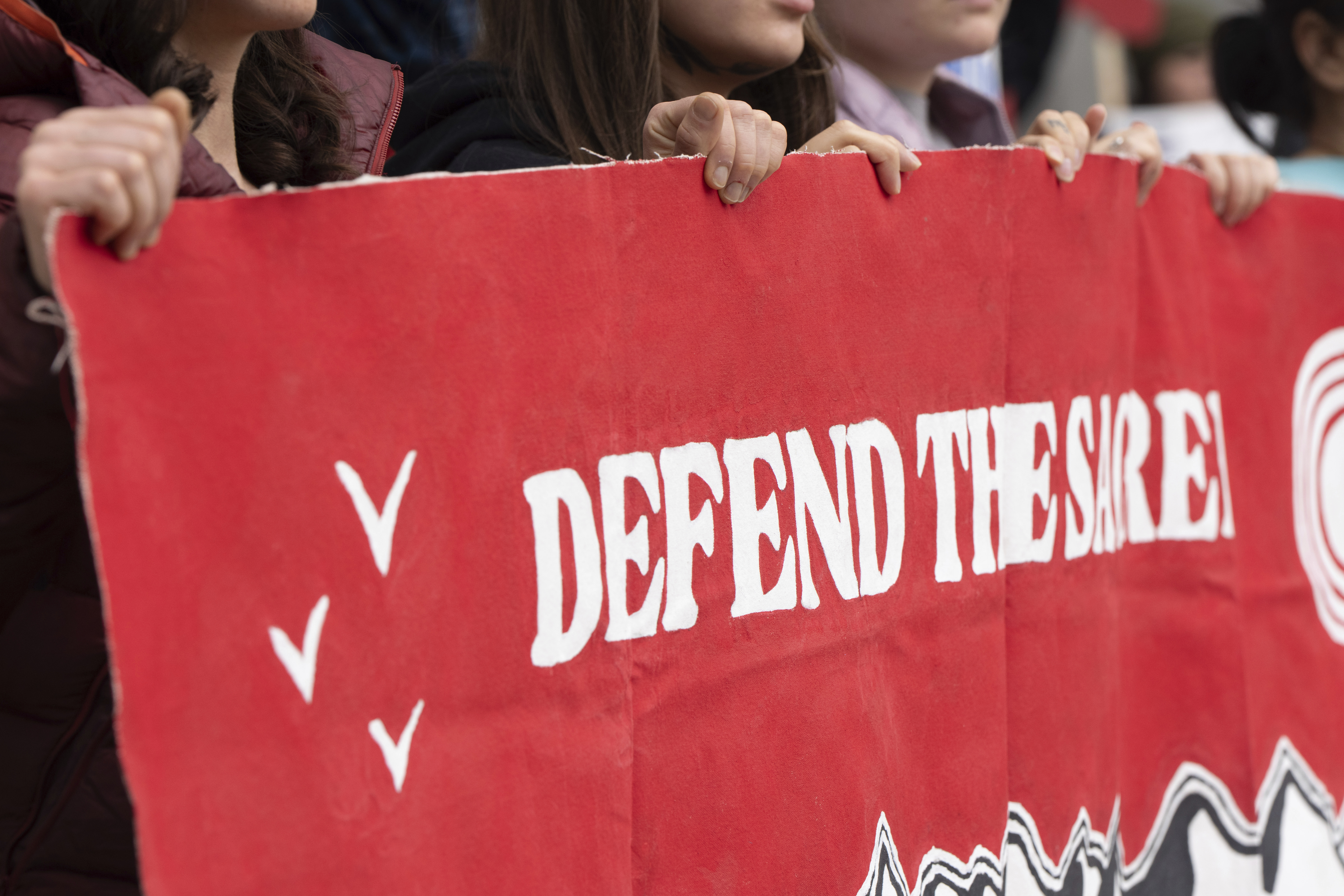 CORRECTS TO ANCHORAGE INSTEAD OF DEADHORSE - People hold a sign during a protest outside the annual Alaska Sustainable Energy Conference on Tuesday, June 3, 2025, in Anchorage, Alaska. (AP Photo/Jenny Kane)