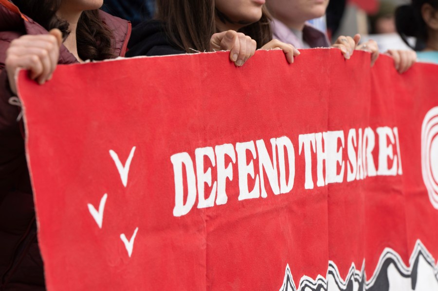CORRECTS TO ANCHORAGE INSTEAD OF DEADHORSE - People hold a sign during a protest outside the annual Alaska Sustainable Energy Conference on Tuesday, June 3, 2025, in Anchorage, Alaska. (AP Photo/Jenny Kane)