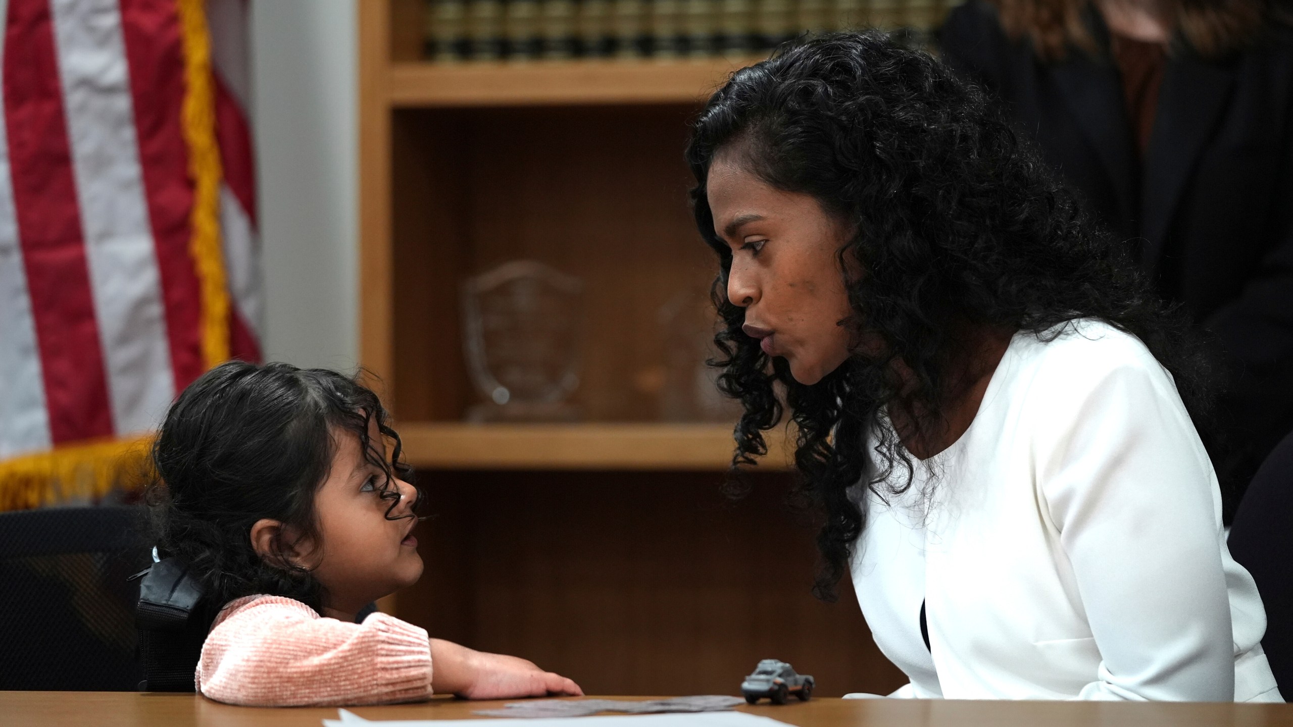Deysi Vargas, left, talks to her 4-year-old daughter, who has short bowel syndrome, at a news conference in Los Angeles, Wednesday, May 28, 2025, after their humanitarian parole was terminated and they were ordered to self-deport. (AP Photo/Jae C. Hong)