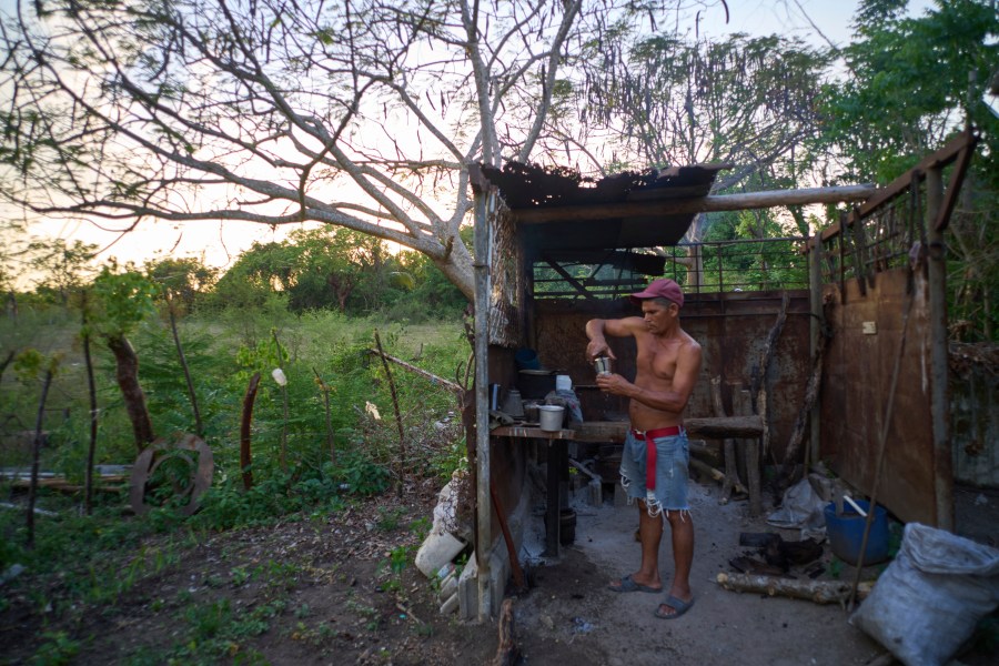 Edinector Vazquez prepares coffee on a charcoal stove behind his home during a blackout in Minas, Havana province, Cuba, Monday, May 26, 2025. (AP Photo/Ramon Espinosa)