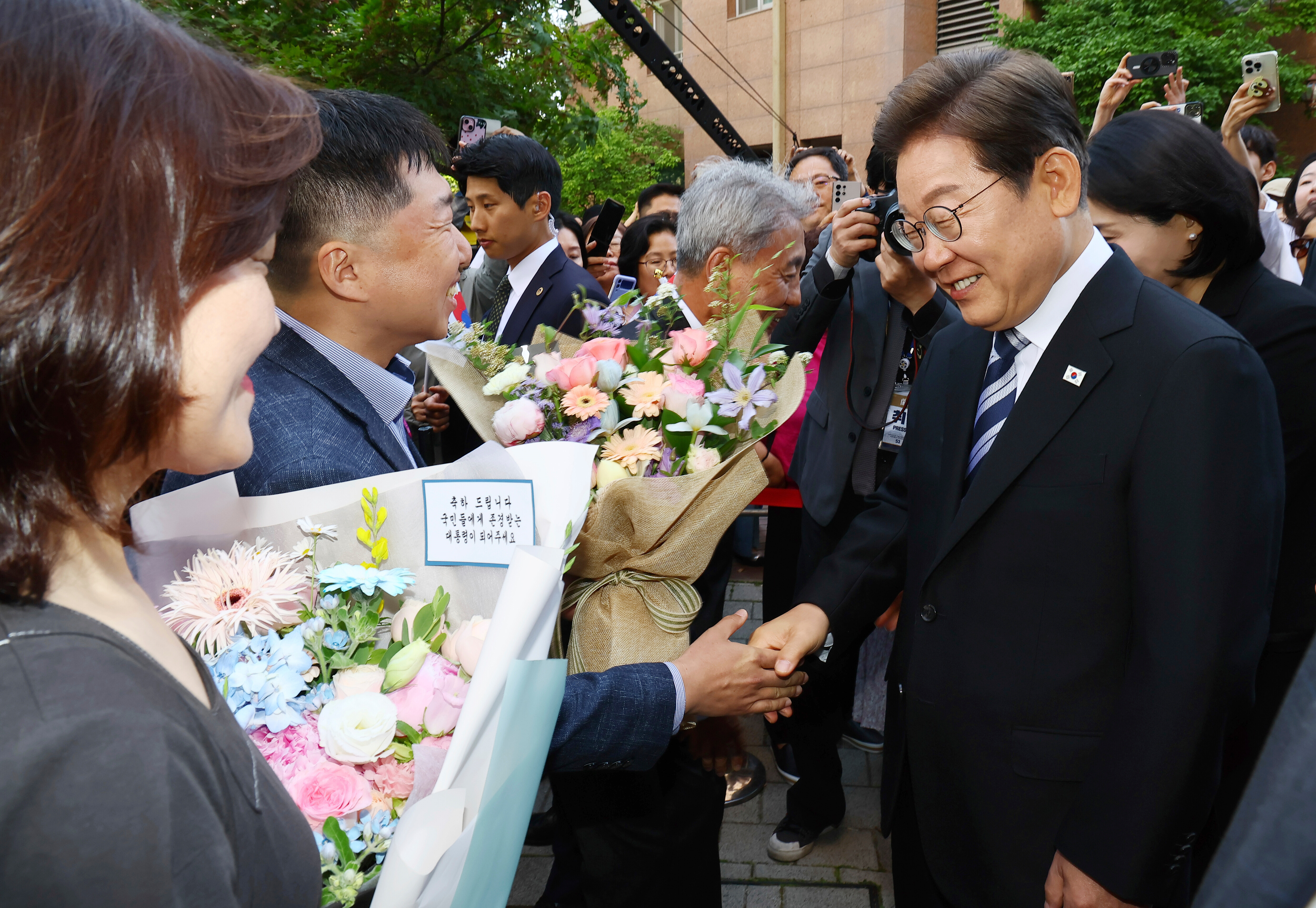 South Korea's newly elected President Lee Jae-myung, right, greets his neighbors and supporters in front of his house in Incheon, South Korea, Wednesday, June 4, 2025. (Han Sang-kyun/Yonhap via AP)