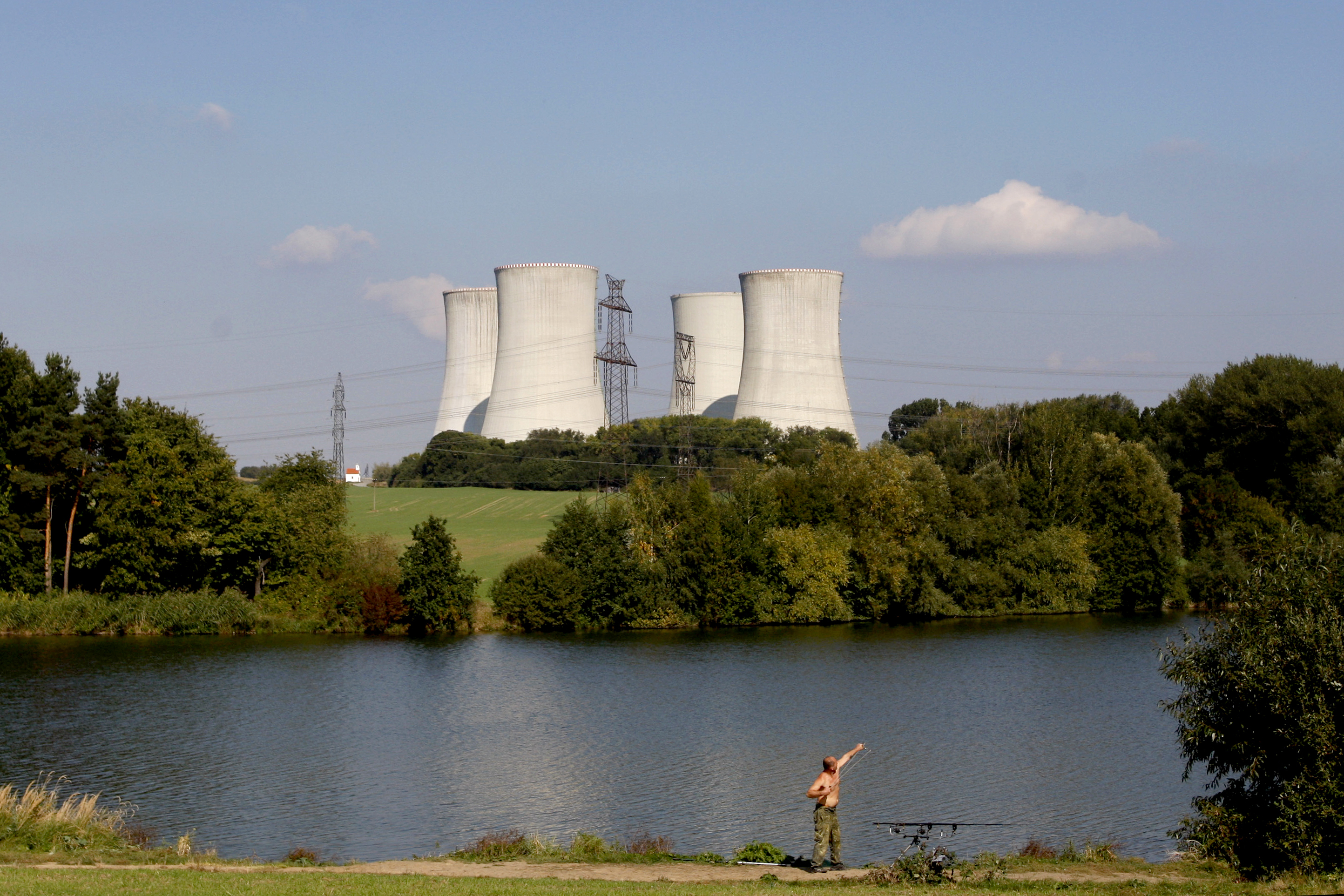 FILE - A man fishes with the towering Dukovany nuclear power plant in the background, in Dukovany, Czech Republic, Sept. 27, 2011. (AP Photo/Petr David Josek, File)