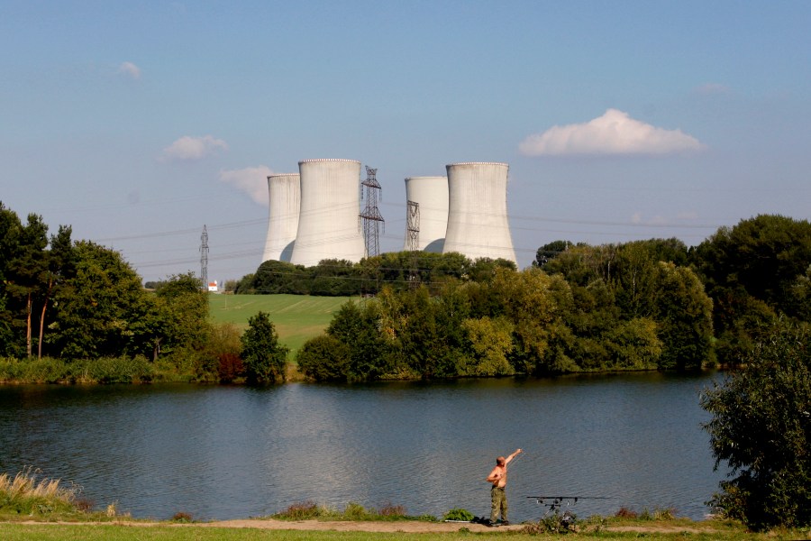 FILE - A man fishes with the towering Dukovany nuclear power plant in the background, in Dukovany, Czech Republic, Sept. 27, 2011. (AP Photo/Petr David Josek, File)