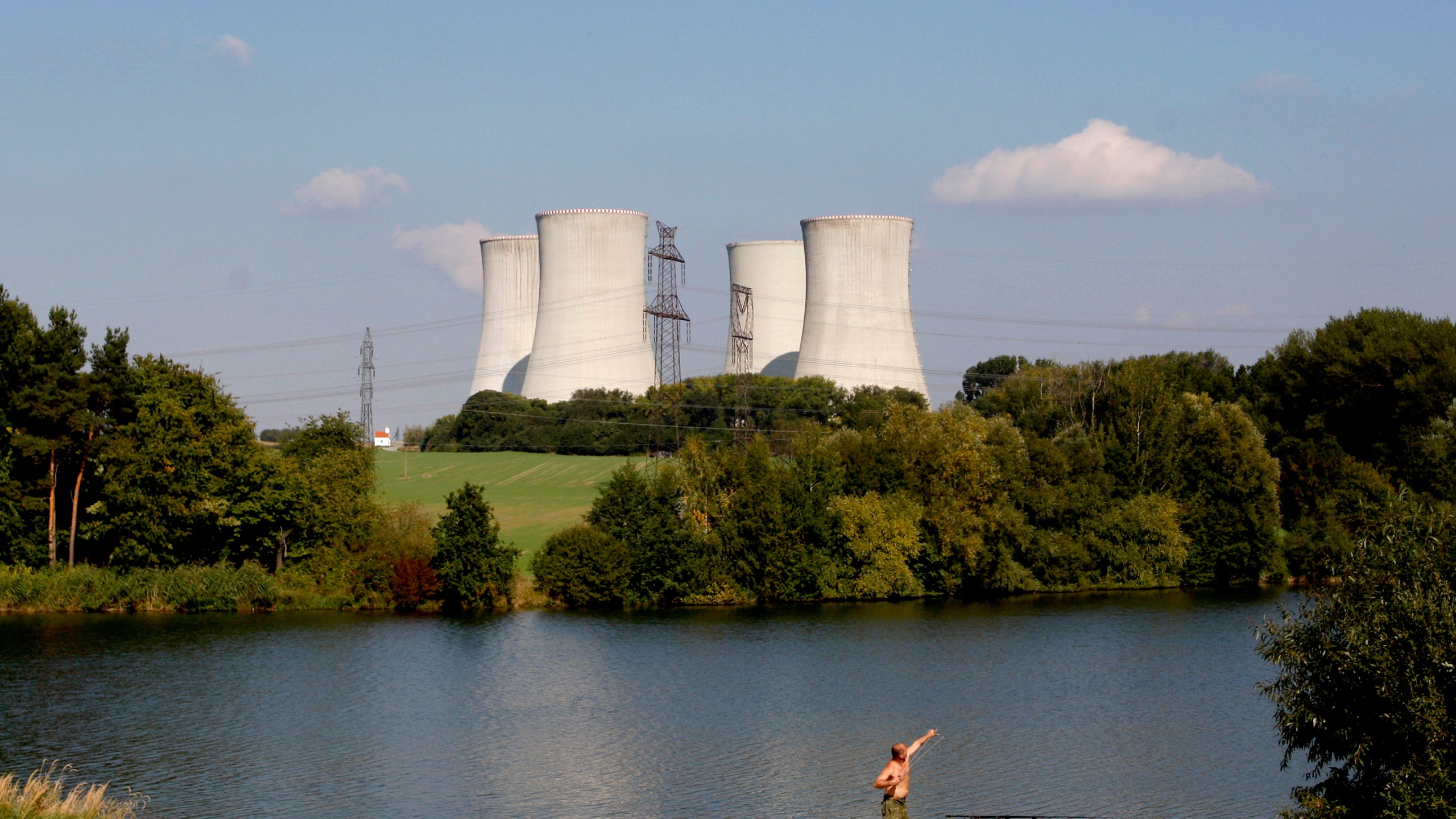 FILE - A man fishes with the towering Dukovany nuclear power plant in the background, in Dukovany, Czech Republic, Sept. 27, 2011. (AP Photo/Petr David Josek, File)