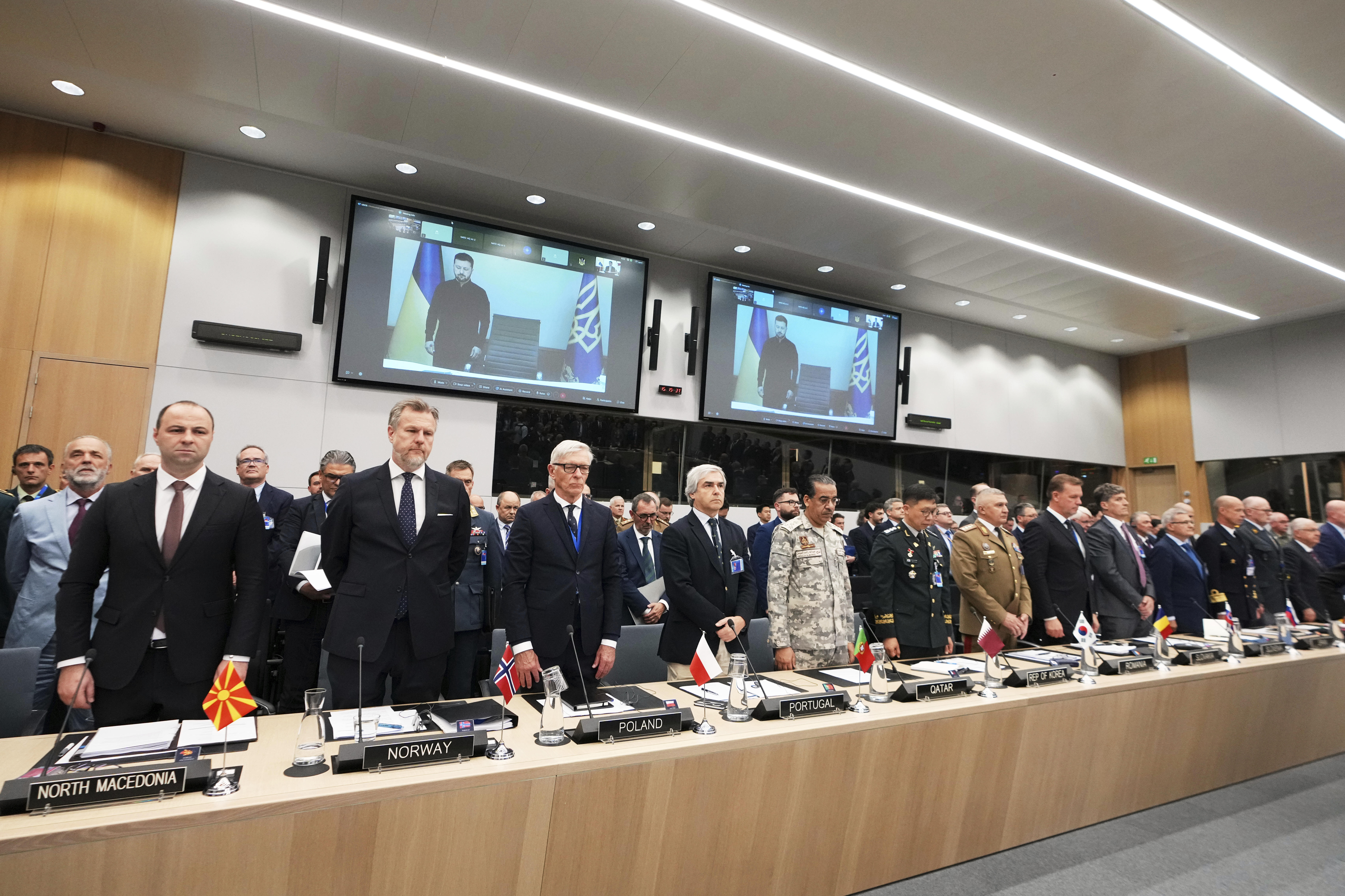 Defense ministers of NATO and Ukraine's President Volodymyr Zelenskyy, via video link, stand for a moment of silence during a meeting of the Ukraine Defense Contact Group at the NATO headquarters in Brussels, Wednesday, June 4, 2025. (AP Photo/Virginia Mayo)
