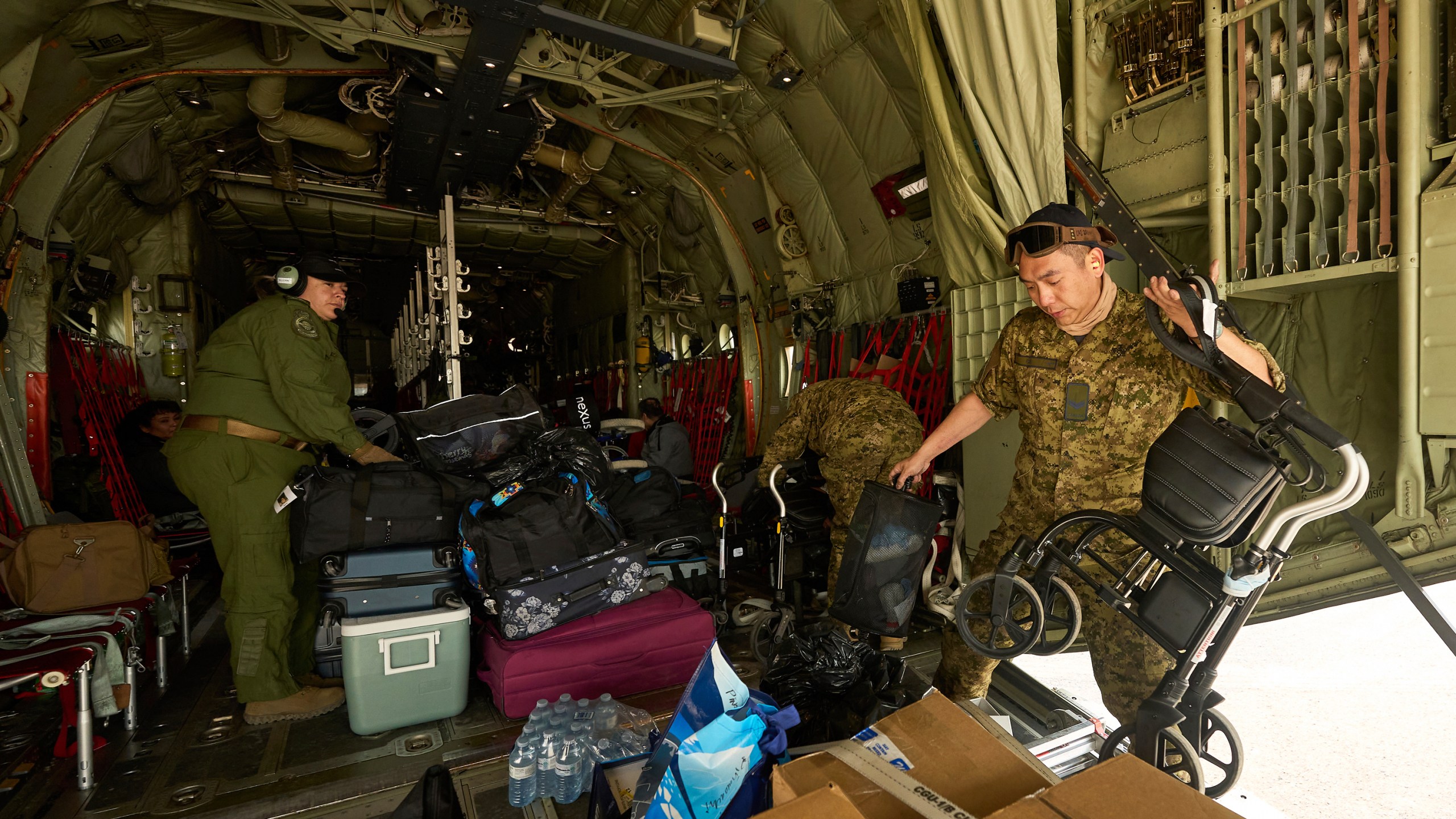 Royal Canadian Air Force Cpl. Ethan Cai helps load cargo as evacuees from Pinaow Wachi Care Home board a C-130 Hercules aircraft in Norway House, Manitoba, Tuesday, June 3, 2025, at the Norway House Airport as crews continue to fight wildfires in northern Manitoba. (David Lipnowski/The Canadian Press via AP)
