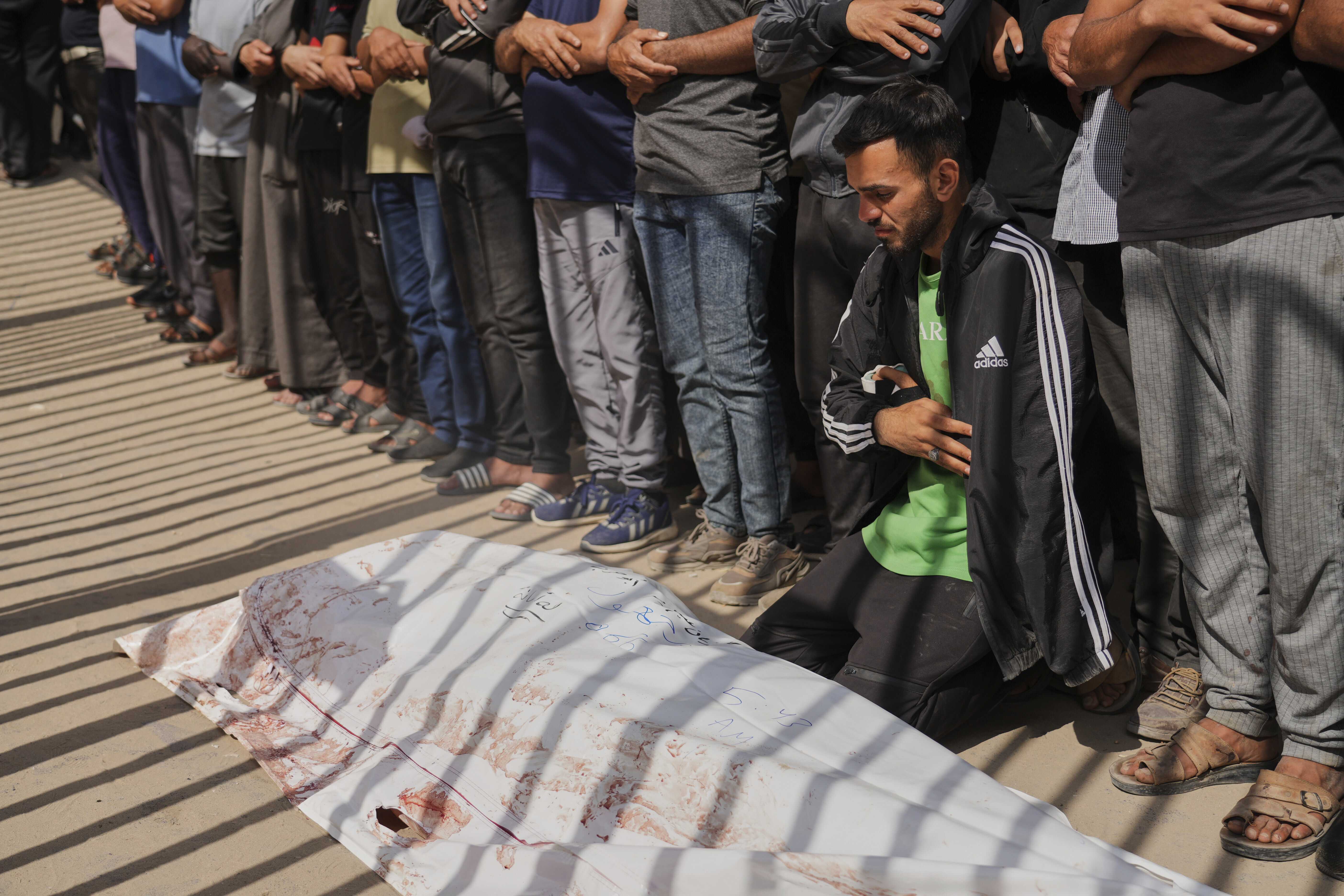 Mourners pray beside the body of Adnan Abu Harb who was killed while heading to a Gaza aid hub, during his funeral at the Nasser Hospital in Khan Younis, southern Gaza Strip, Tuesday, June 3, 2025. (AP Photo/Abdel Kareem Hana)