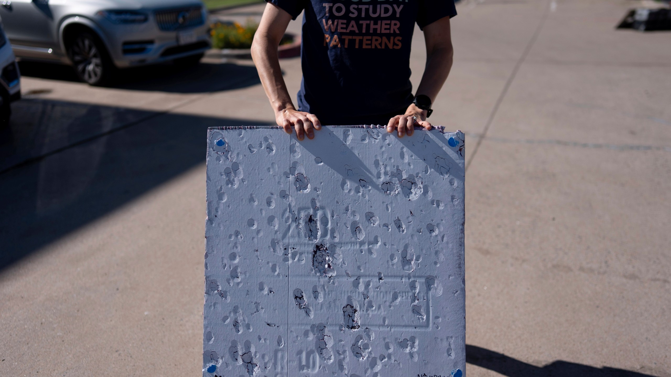 Hannah Vagasky holds a foam board hail pad covered with impact dents in a parking lot Tuesday, June 3, 2025, in Shamrock, Texas, as the team prepares for a day of hailstorm chasing. The hail pad is used to measure the size, angle of impact and intensity of hail. (AP Photo/Carolyn Kaster)