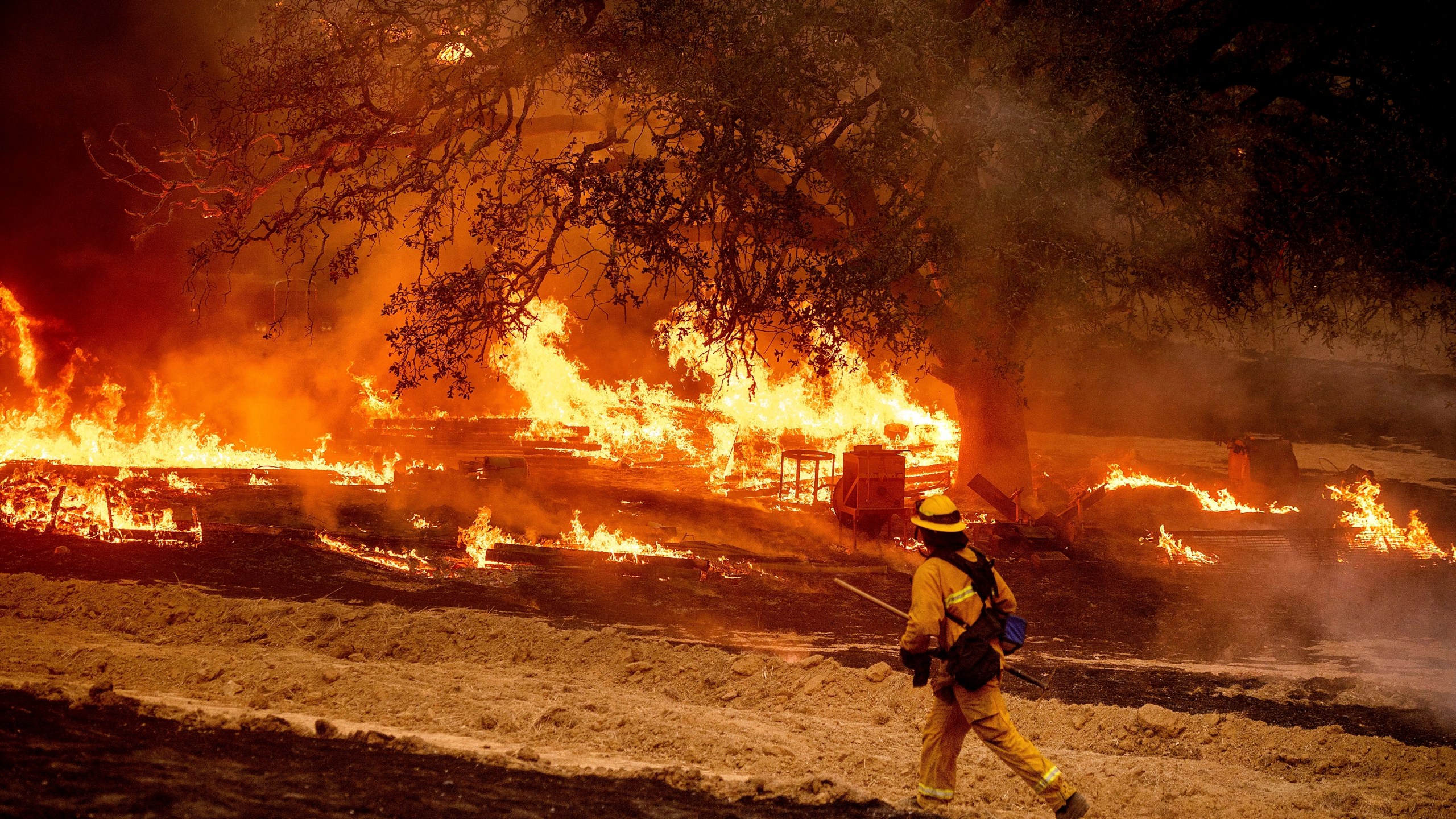 FILE - A firefighter passes flames while battling the Glass Fire in a Calistoga, Calif., vineyard Oct. 1, 2020. (AP Photo/Noah Berger, File)