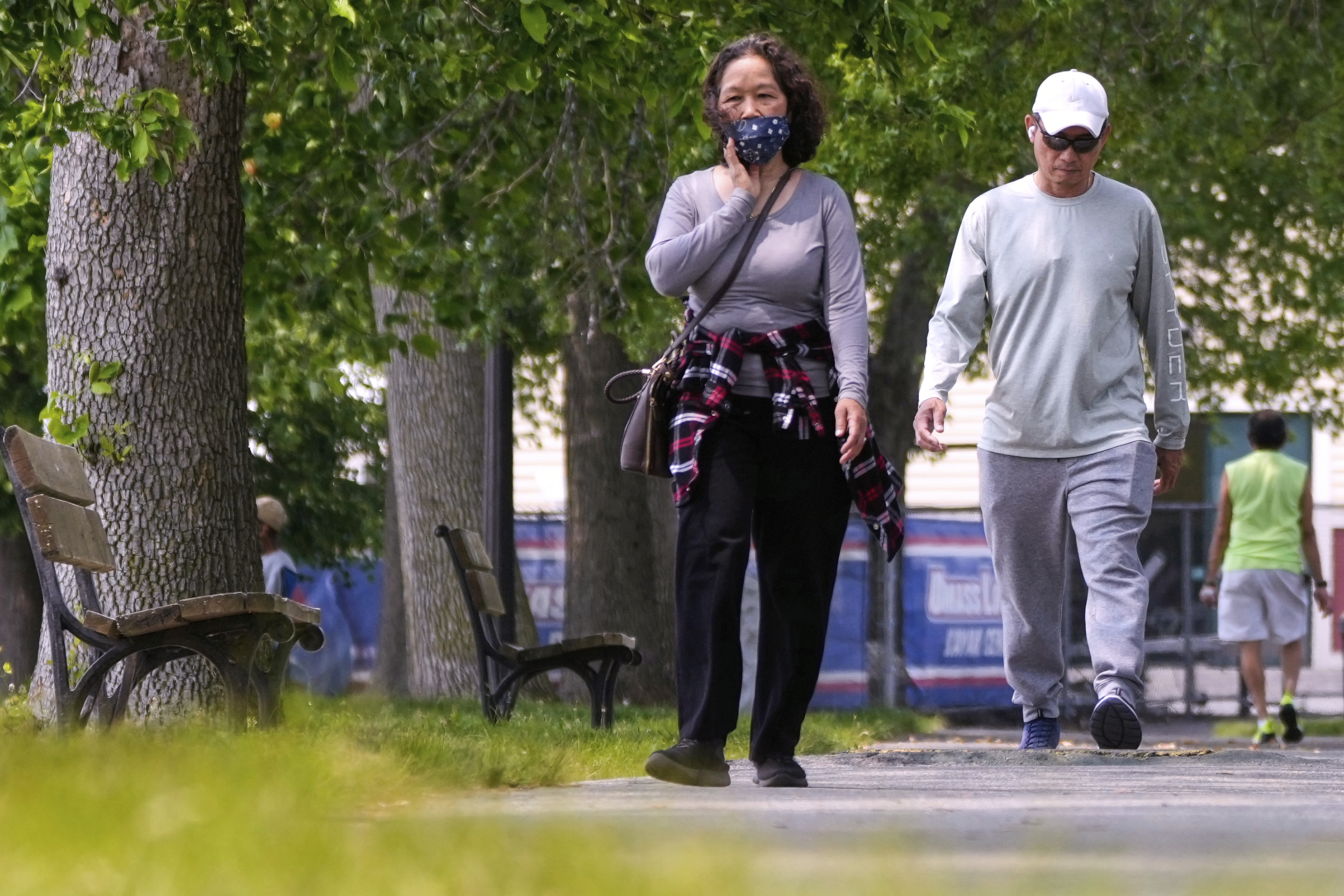 A woman wears a protective mask while walking along the banks of the Merrimack River, Wednesday, June 4, 2025, in Lowell, Mass. (AP Photo/Charles Krupa)