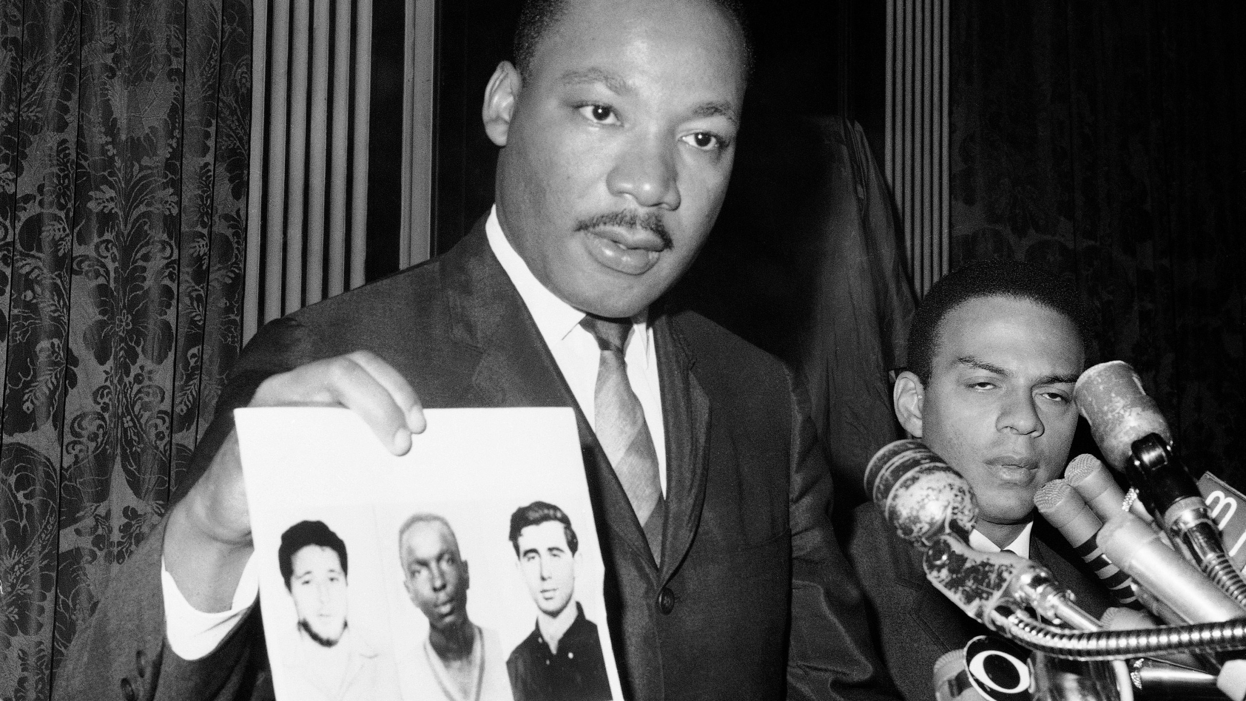 FILE - Civil rights leader Martin Luther King Jr. displays pictures of three civil rights workers, who were slain in Mississippi the summer before, from left Michael Schwerner, James Chaney, and Andrew Goodman, at a news conference Dec. 4, 1964, in New York, where he commended the FBI for its arrests in Mississippi in connection with the slayings. (AP Photo/JL, File)