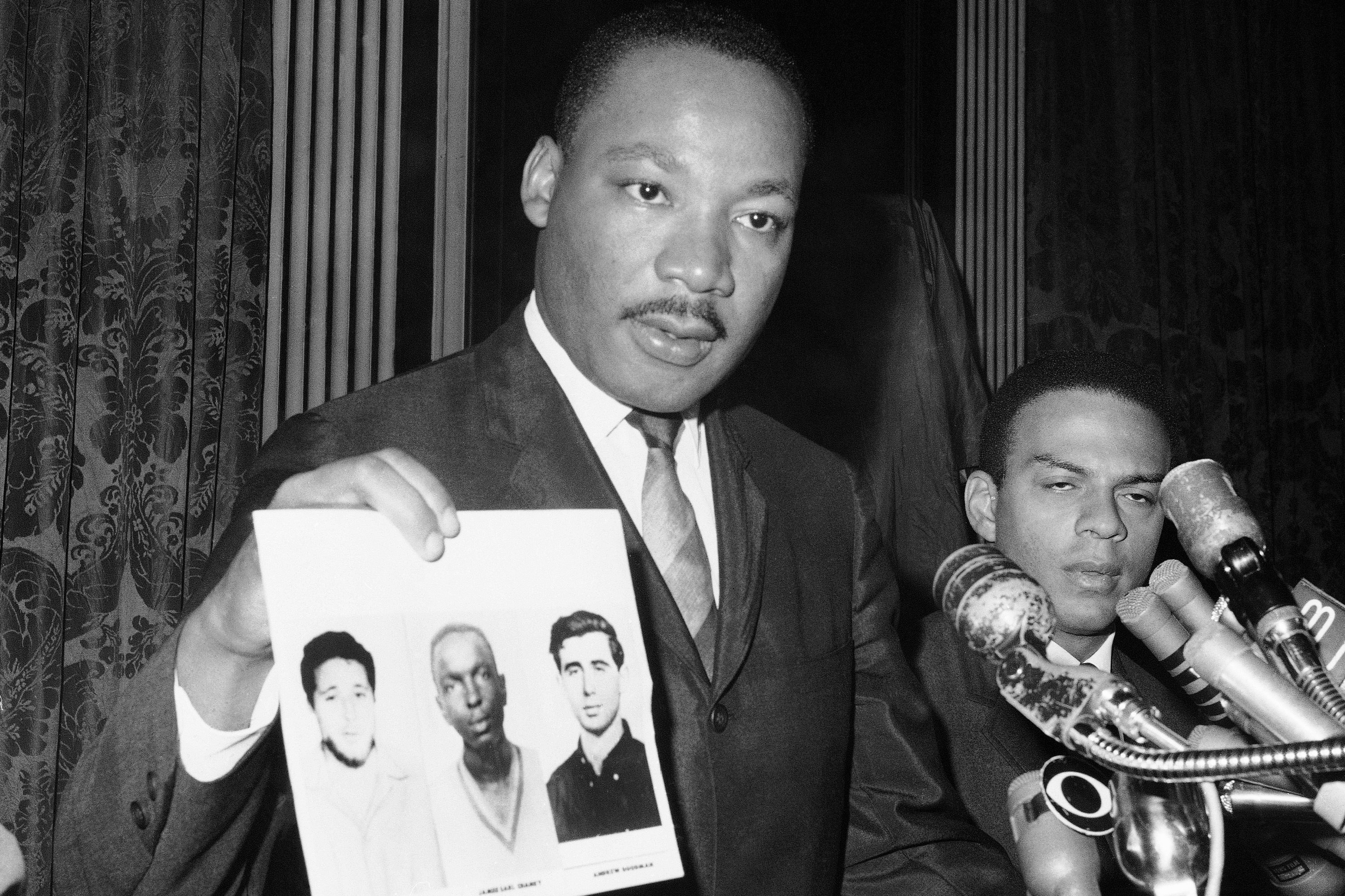 FILE - Civil rights leader Martin Luther King Jr. displays pictures of three civil rights workers, who were slain in Mississippi the summer before, from left Michael Schwerner, James Chaney, and Andrew Goodman, at a news conference Dec. 4, 1964, in New York, where he commended the FBI for its arrests in Mississippi in connection with the slayings. (AP Photo/JL, File)