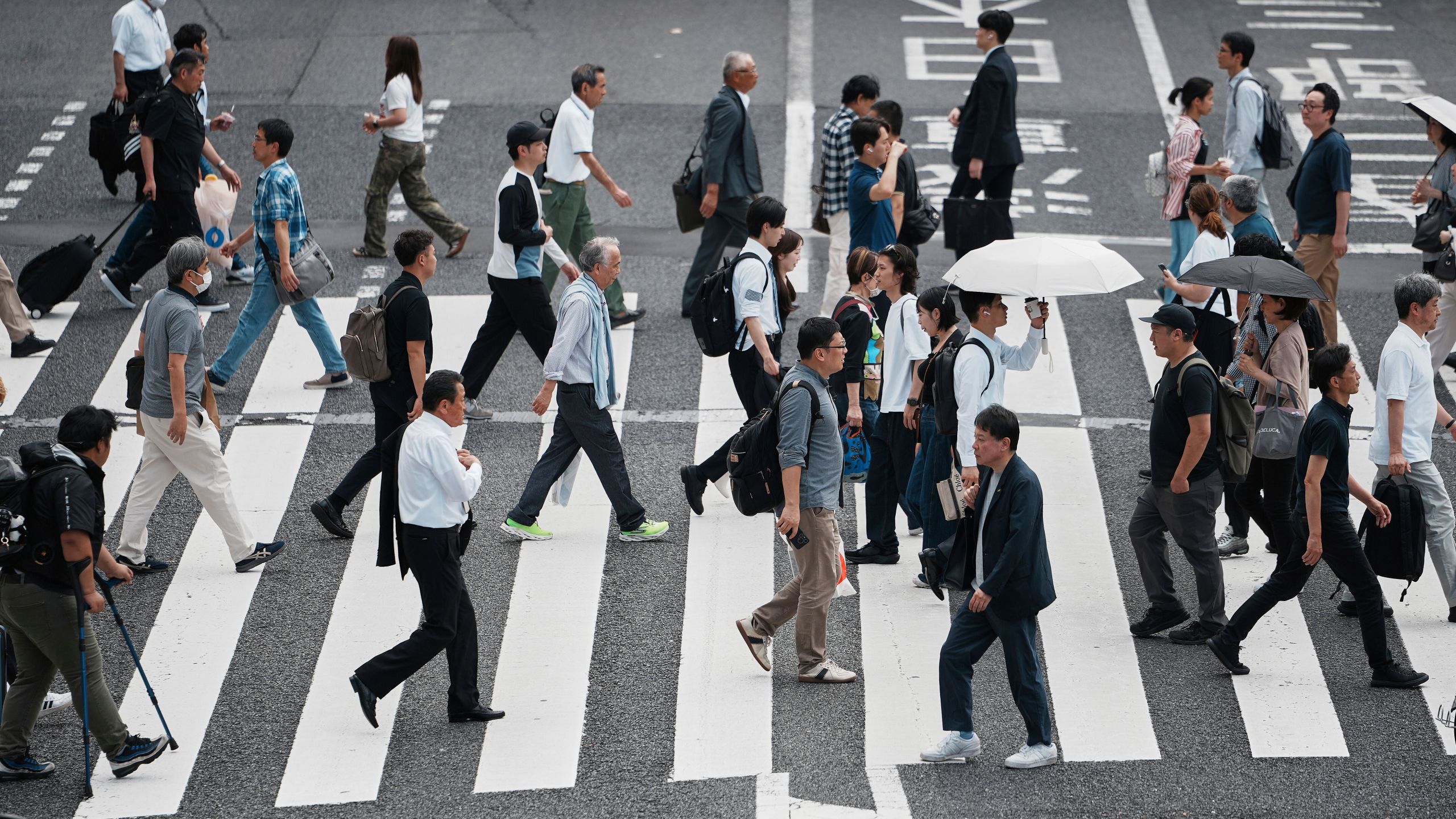 People walk along a pedestrian crossing at a shopping street Wednesday, June 4, 2025, in Tokyo. (AP Photo/Eugene Hoshiko)