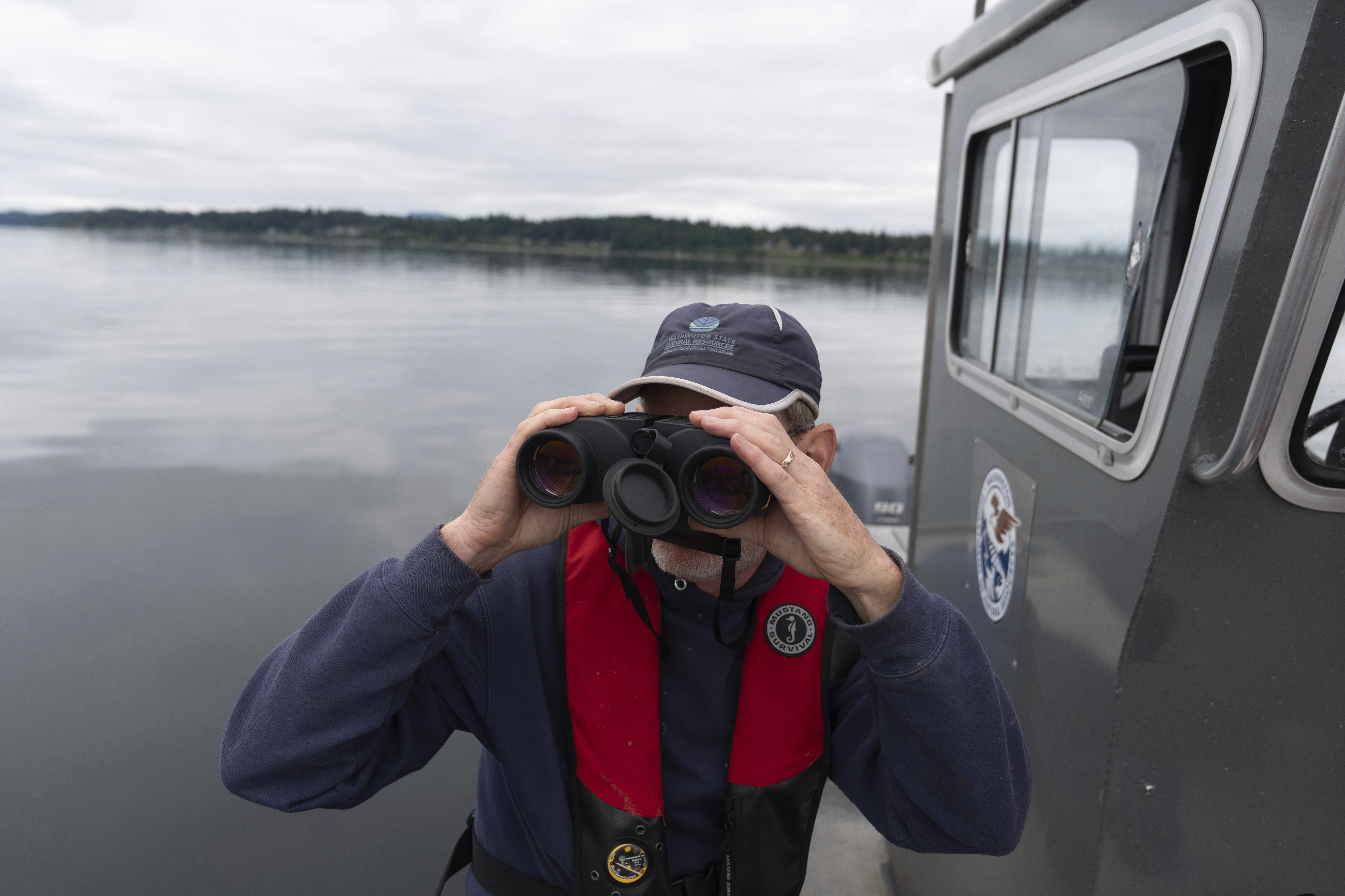 Washington Department of Natural Resources' Lowell Dickson watches as a helicopter moves an abandoned ship on Wednesday, June 4, 2025, in Olympia, Wash. (AP Photo/Jenny Kane)