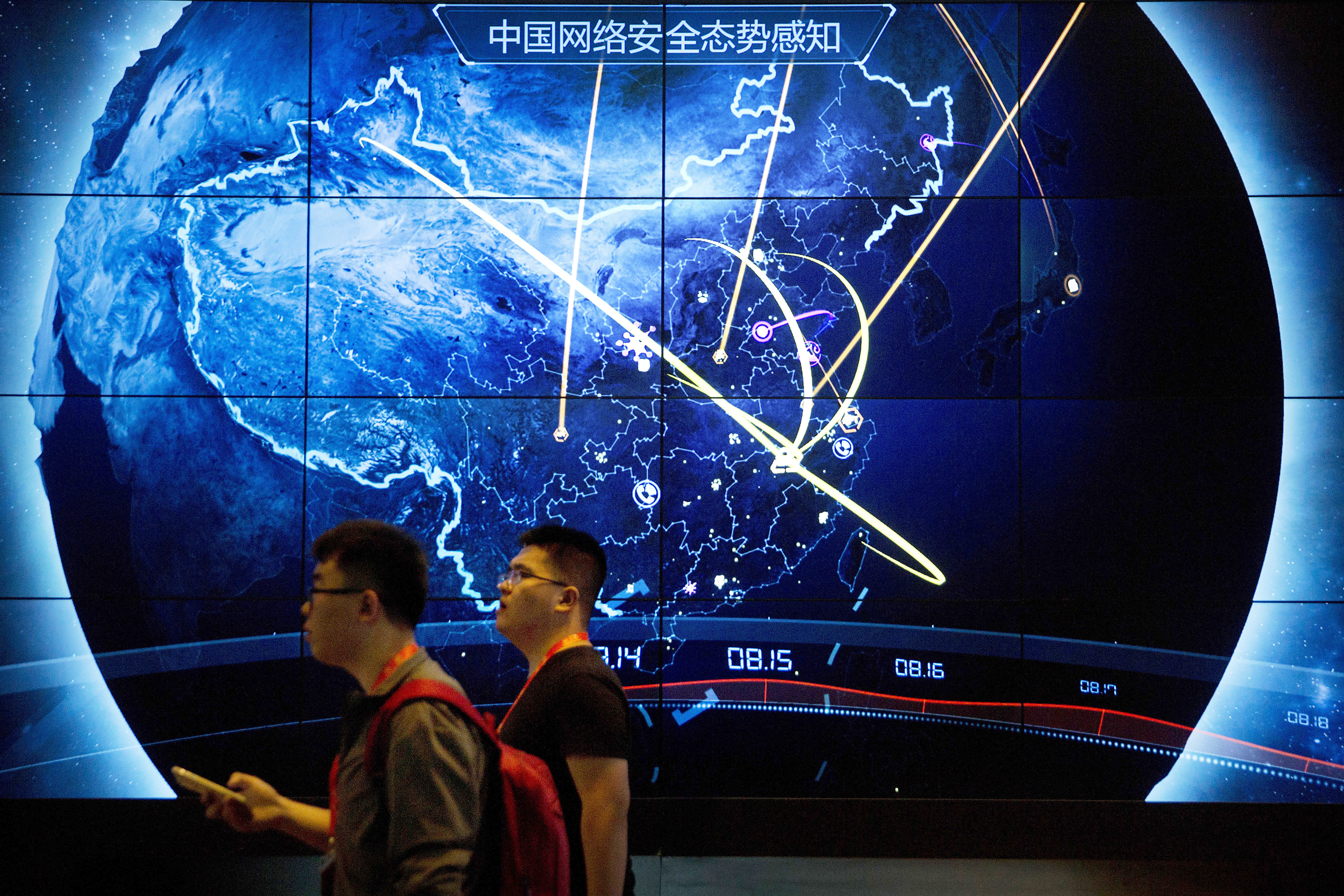 FILE - Attendees walk past an electronic display showing recent cyberattacks in China at the China Internet Security Conference in Beijing, on Sept. 12, 2017. (AP Photo/Mark Schiefelbein, File)