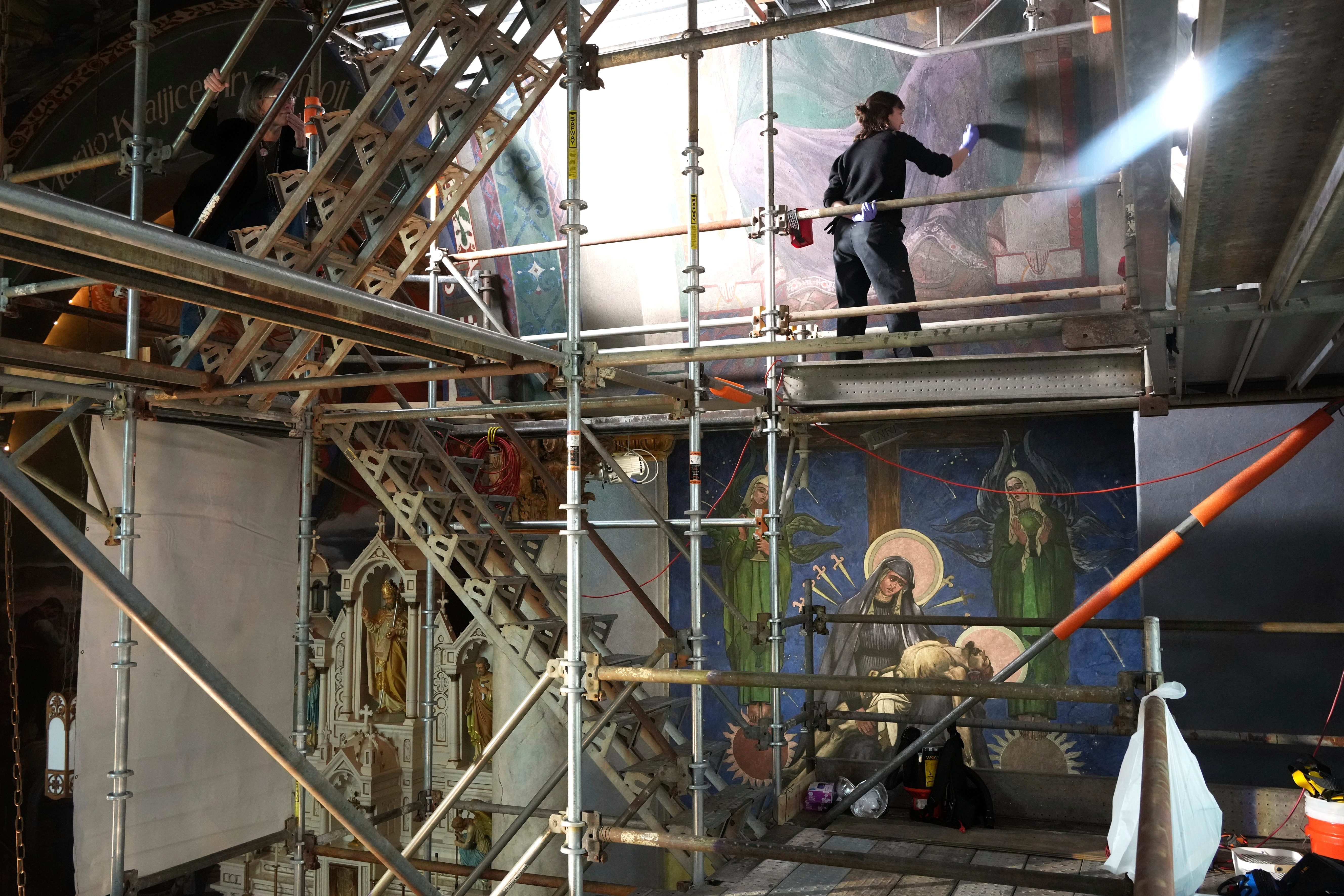Working on a 32-foot-tall scaffold, art conservator Kate Pirelli works on cleaning a mural by Max Vanka inside St. Nicholas Croatian Catholic Church in Millvale, Pa., Monday, May 19, 2025. (AP Photo/Gene J. Puskar)