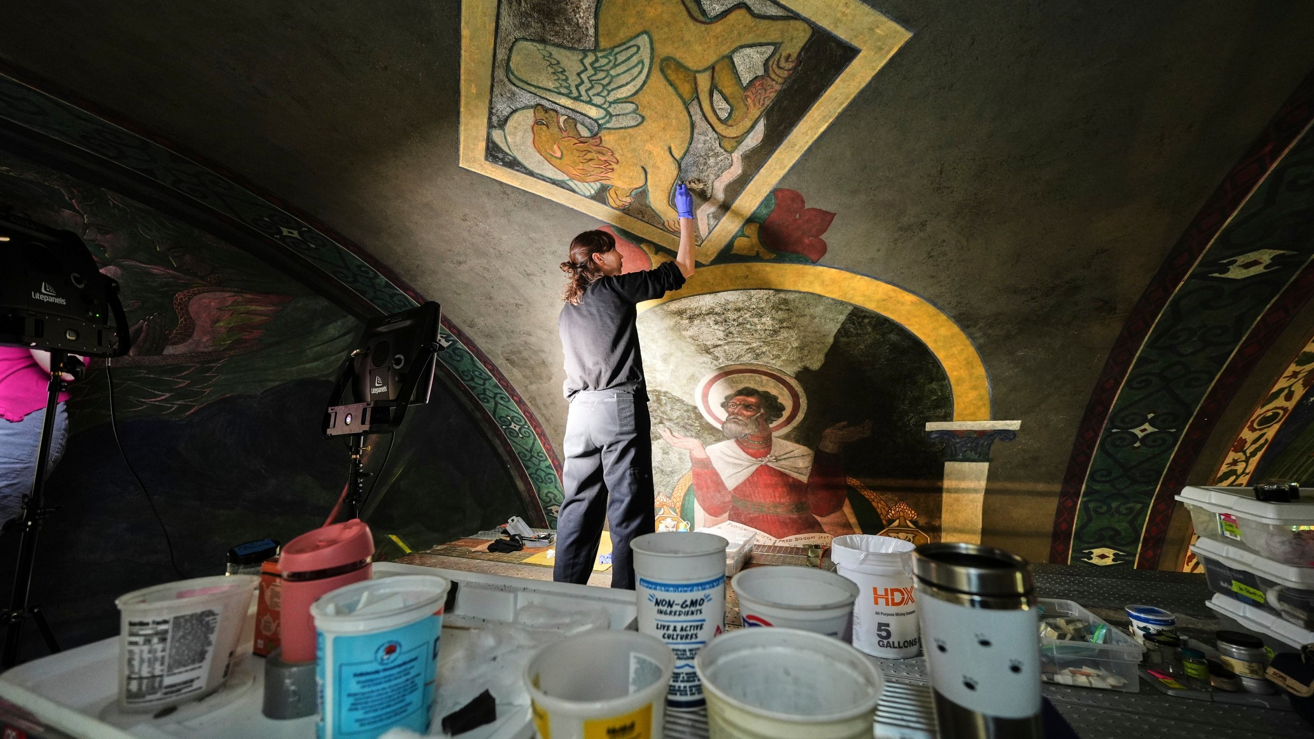 Standing on a 32-foot-tall scaffold, art conservationist Kate Pirelli works on cleaning a mural by Max Vanka depicting a lion and St. Mark inside St. Nicholas Croatian Catholic Church in Millvale, Pa., Monday, May 19, 2025. (AP Photo/Gene J. Puskar)