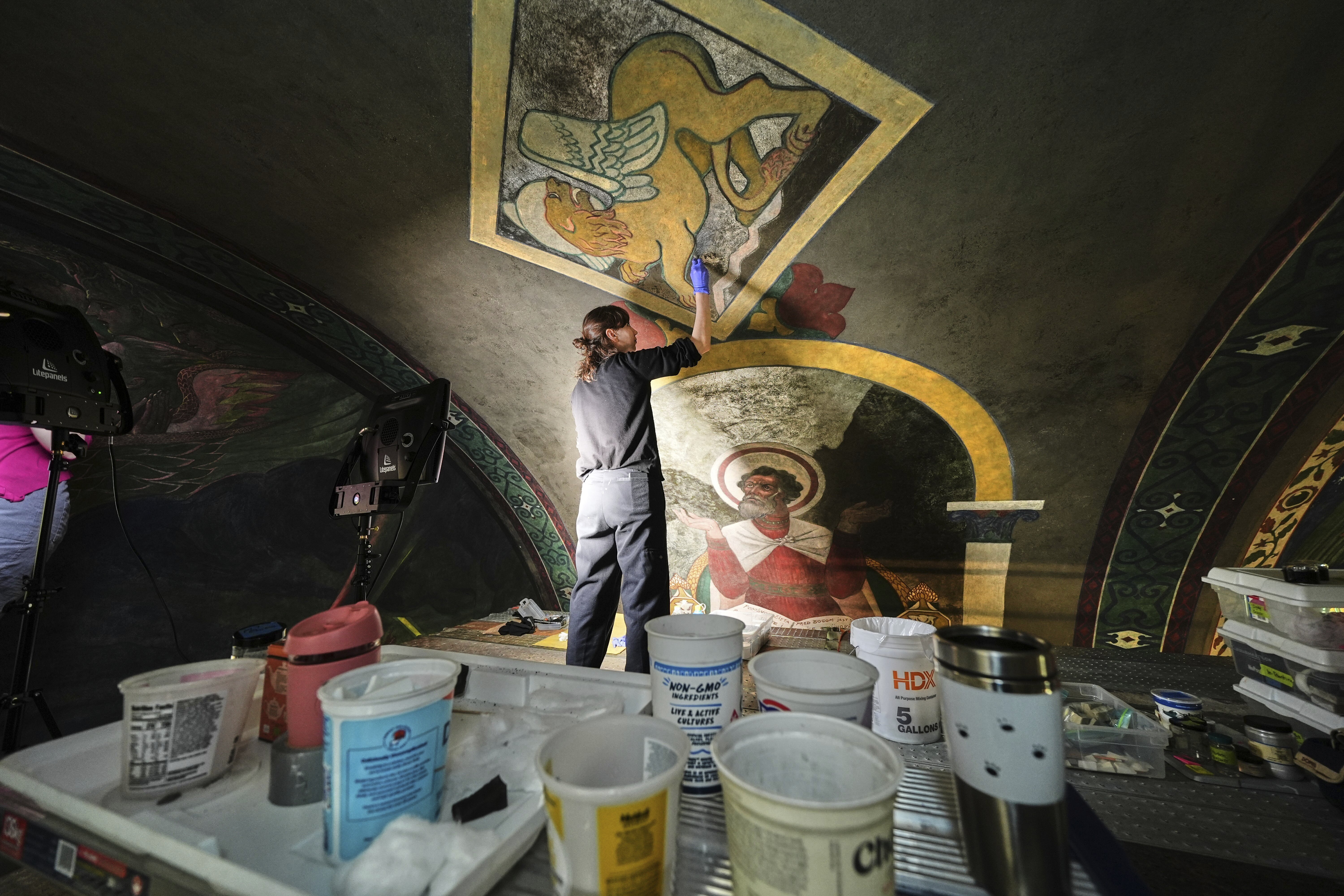 Standing on a 32-foot-tall scaffold, art conservationist Kate Pirelli works on cleaning a mural by Max Vanka depicting a lion and St. Mark inside St. Nicholas Croatian Catholic Church in Millvale, Pa., Monday, May 19, 2025. (AP Photo/Gene J. Puskar)
