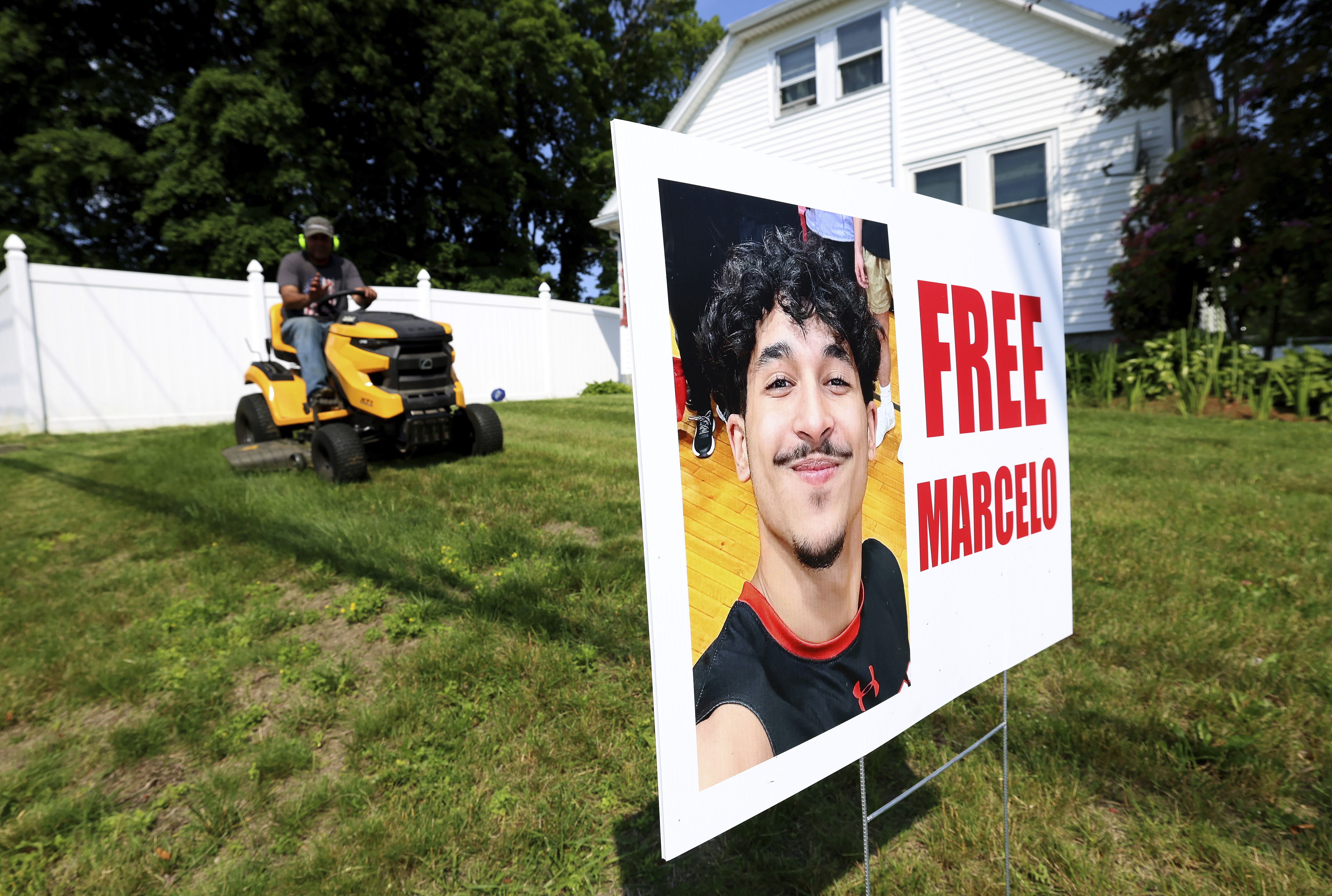 A homeowner around a sign supporting Marcelo Gomes Da Silva, who was arrested on his way to volleyball practice last weekend, on Thursday, June 5, 2025 in Milford, Mass. (AP Photo/Mark Stockwell)