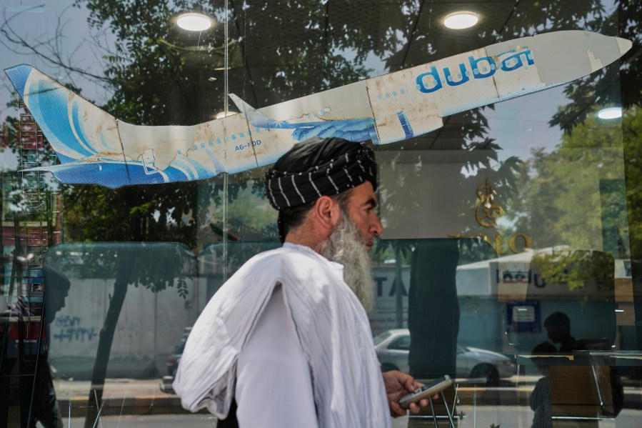 An Afghan man passes in front of an air travel agency in Kabul, Afghanistan, Thursday, June 5, 2025. (AP Photo/Ebrahim Noroozi)