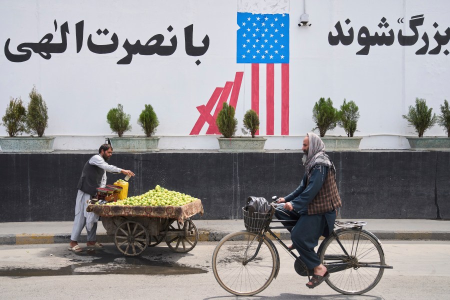 A cyclist passes in front of the former US embassy while a vendor waits for customers, in Kabul, Afghanistan, Thursday, June 5, 2025. (AP Photo/Ebrahim Noroozi)