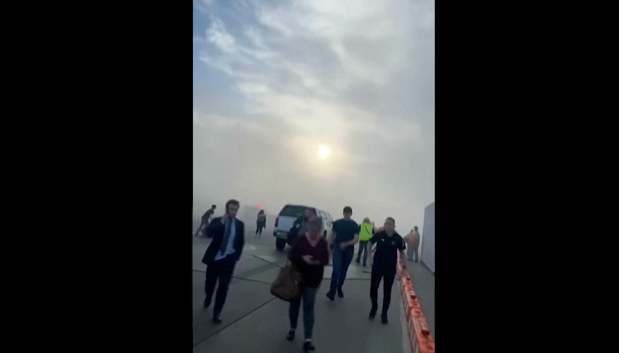 FILE - In this image taken from video provided by Justus Rainey, passengers move away from a plane as smoke surrounded the aircraft, in Denver, March 13, 2025. (Justus Rainey via AP, File)