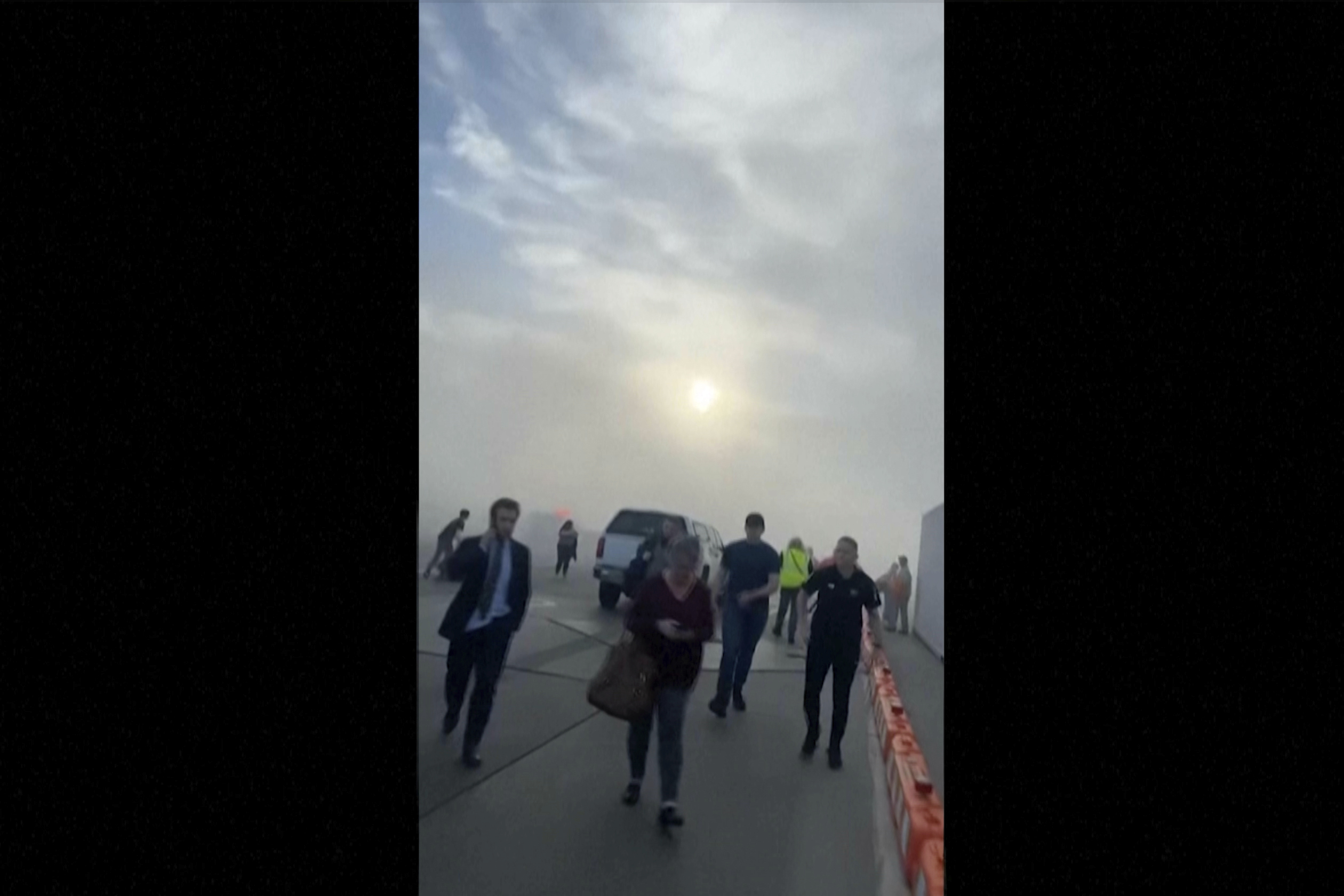 FILE - In this image taken from video provided by Justus Rainey, passengers move away from a plane as smoke surrounded the aircraft, in Denver, March 13, 2025. (Justus Rainey via AP, File)