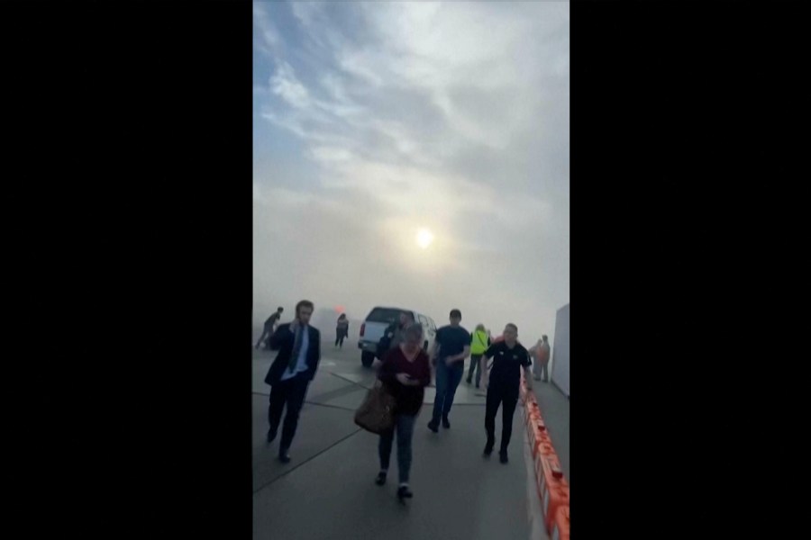 FILE - In this image taken from video provided by Justus Rainey, passengers move away from a plane as smoke surrounded the aircraft, in Denver, March 13, 2025. (Justus Rainey via AP, File)