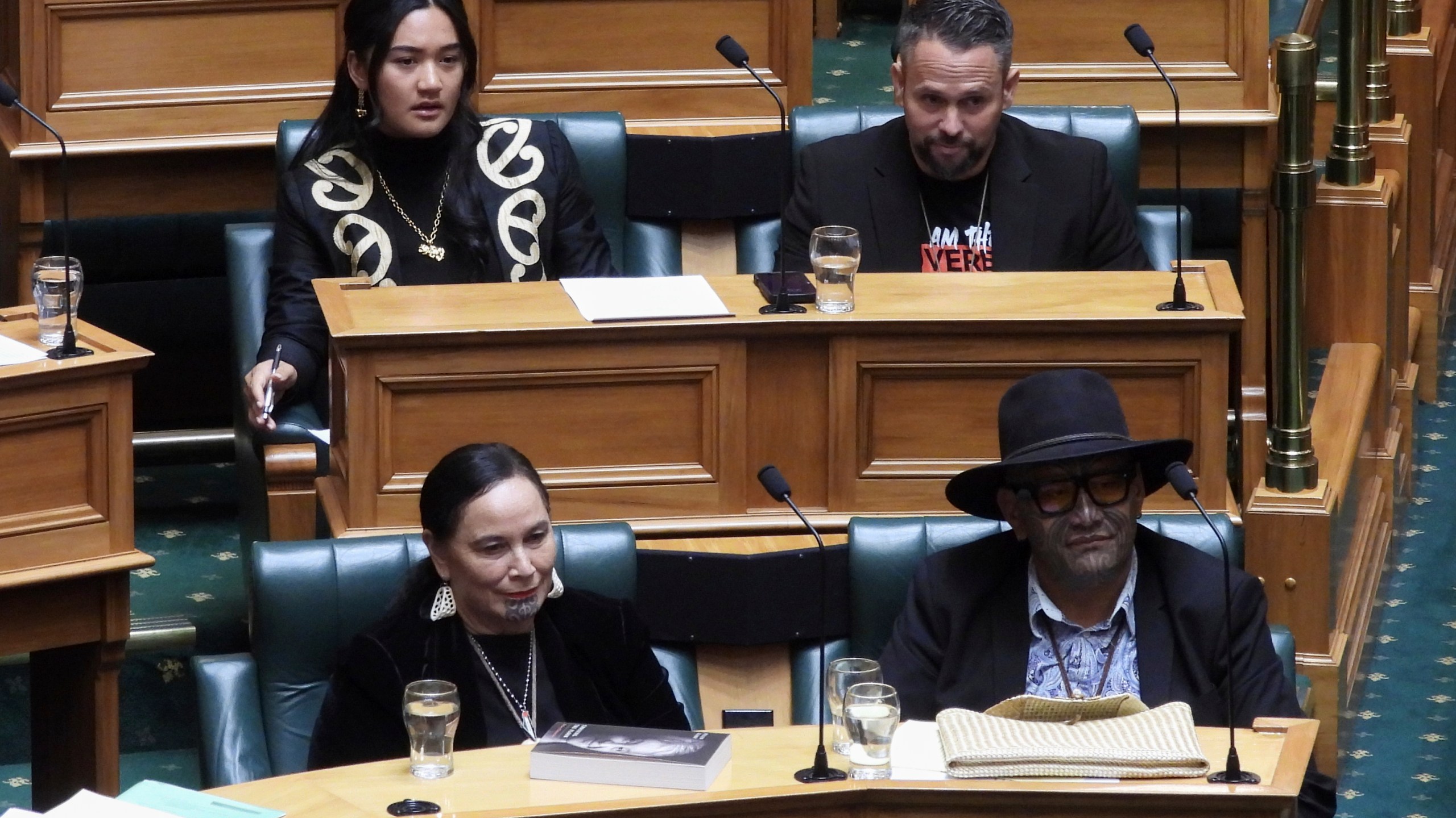 New Zealand lawmakers Hana-Rāwhiti Maipi-Clarke, top left, Debbie Ngarewa-Packer, bottom left, and Rawiri Waititi, bottom right, watch as other legislators debate their proposed bans in parliament in Wellington on Thursday, June 5, 2025. (AP Photo/Charlotte Graham-McLay)
