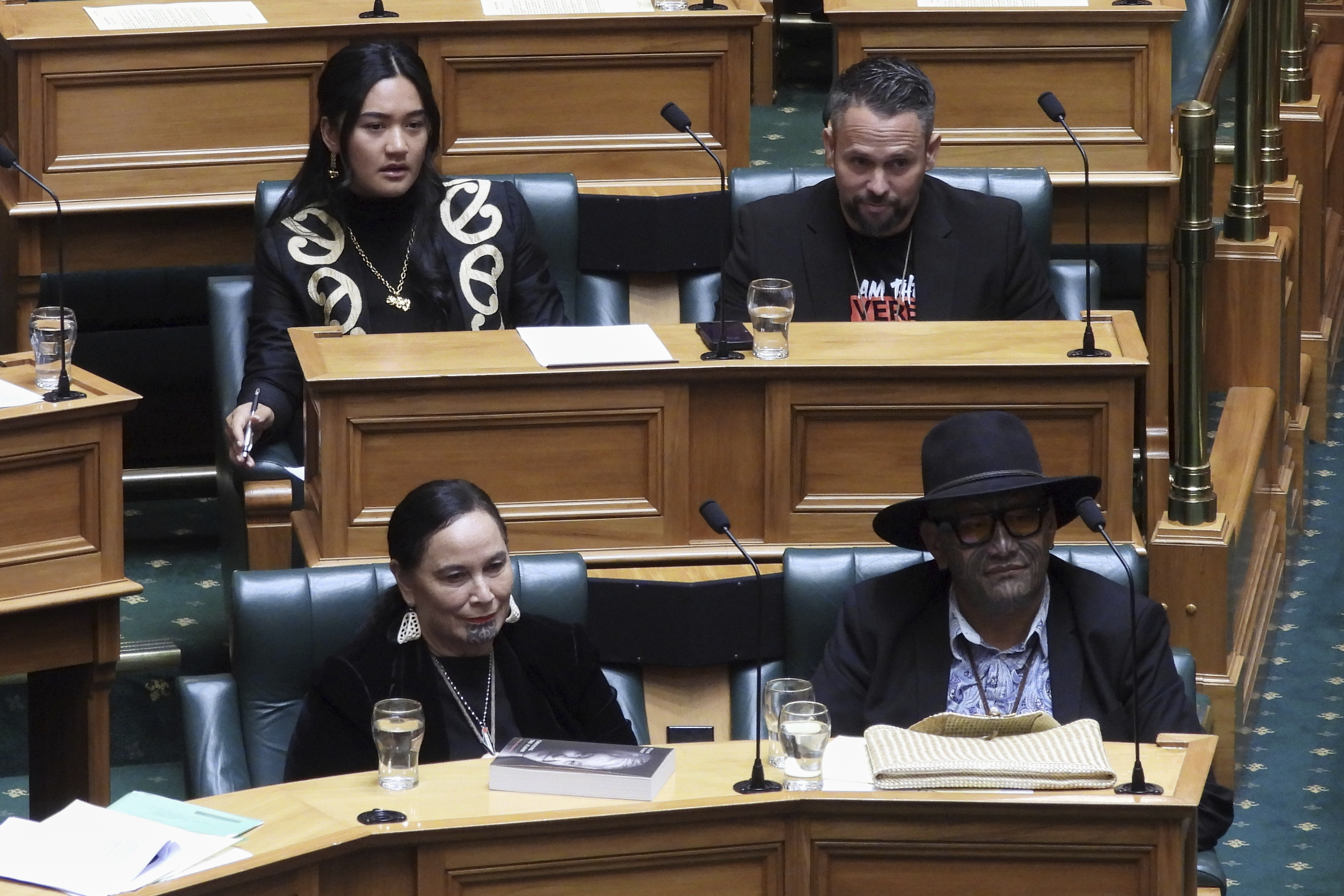 New Zealand lawmakers Hana-Rāwhiti Maipi-Clarke, top left, Debbie Ngarewa-Packer, bottom left, and Rawiri Waititi, bottom right, watch as other legislators debate their proposed bans in parliament in Wellington on Thursday, June 5, 2025. (AP Photo/Charlotte Graham-McLay)