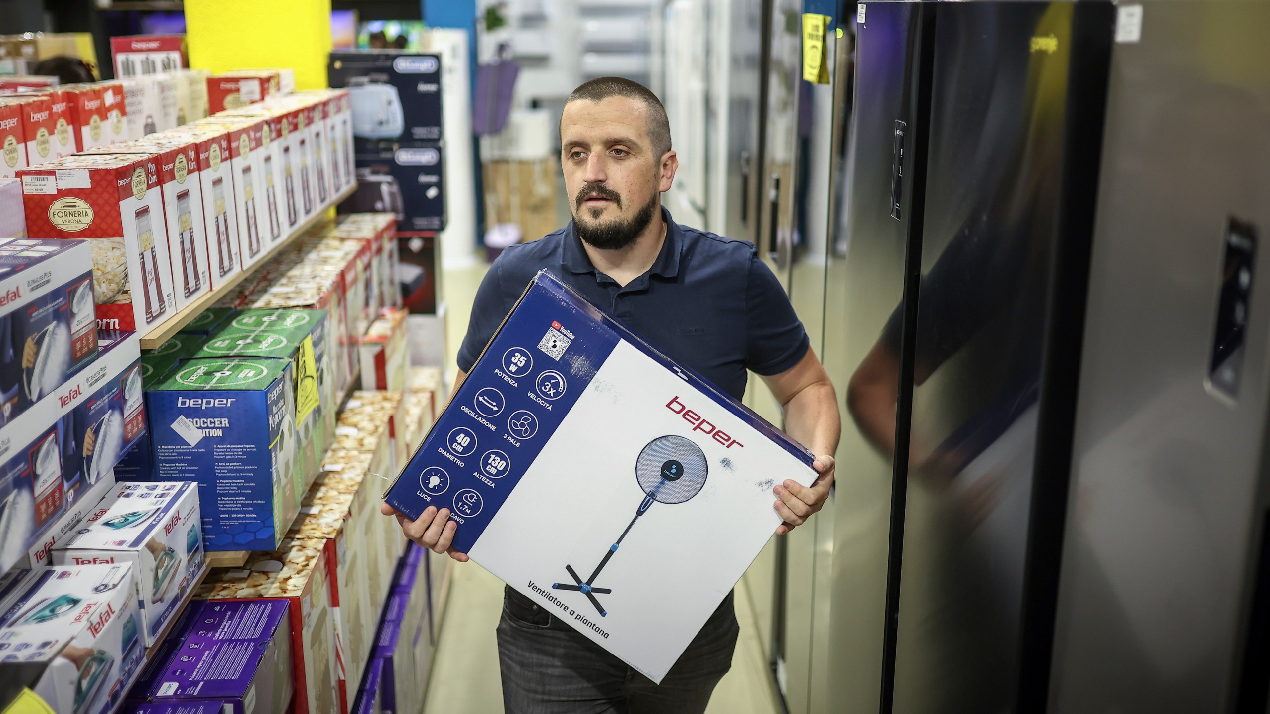 Tarik Fatic, one of the owners of "Only fools and horses ltd." home appliance store, brings a fan to a customer in Hadzici, suburb of Sarajevo, Bosnia, Wednesday, June 4, 2025. (AP Photo/Armin Durgut)