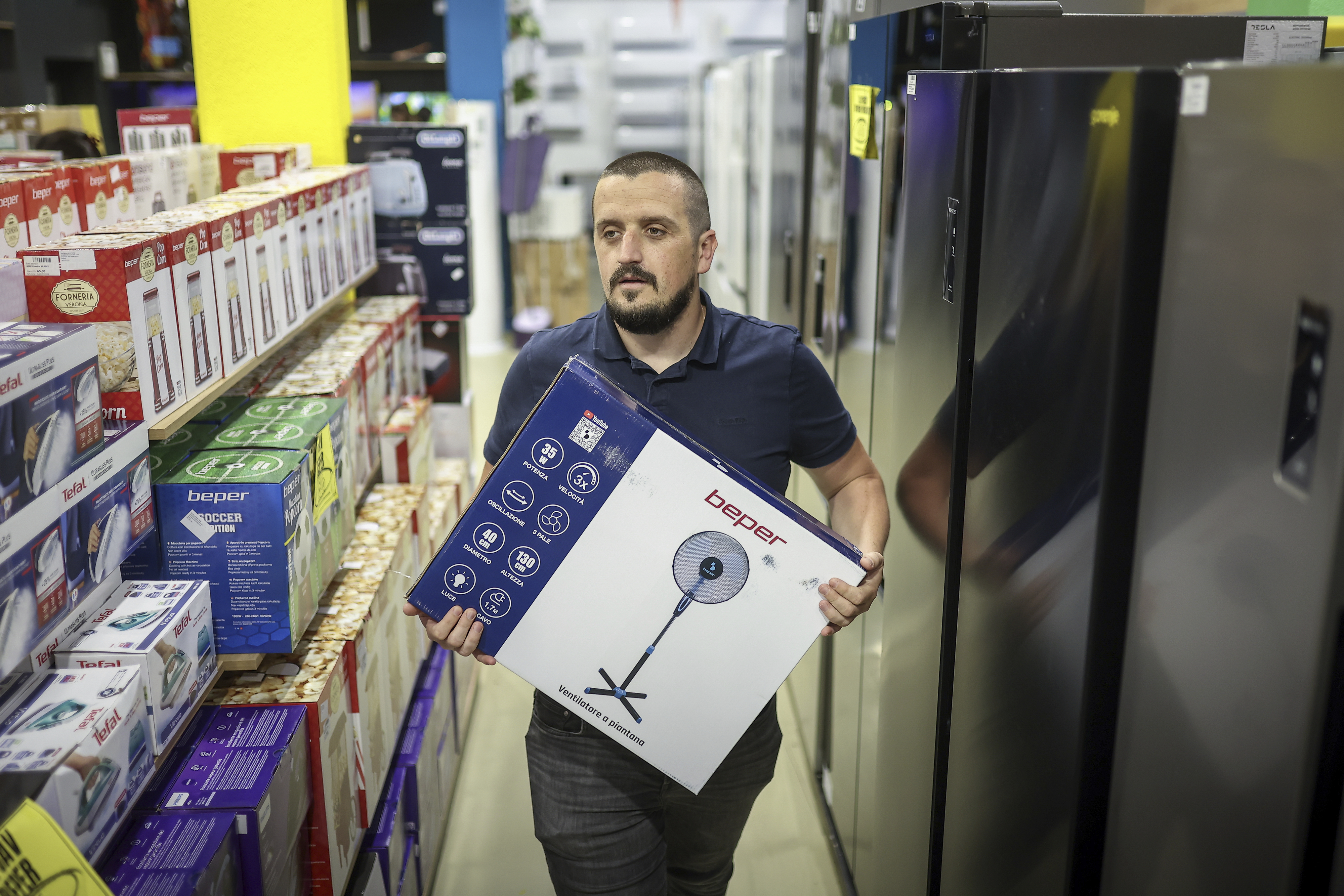 Tarik Fatic, one of the owners of "Only fools and horses ltd." home appliance store, brings a fan to a customer in Hadzici, suburb of Sarajevo, Bosnia, Wednesday, June 4, 2025. (AP Photo/Armin Durgut)