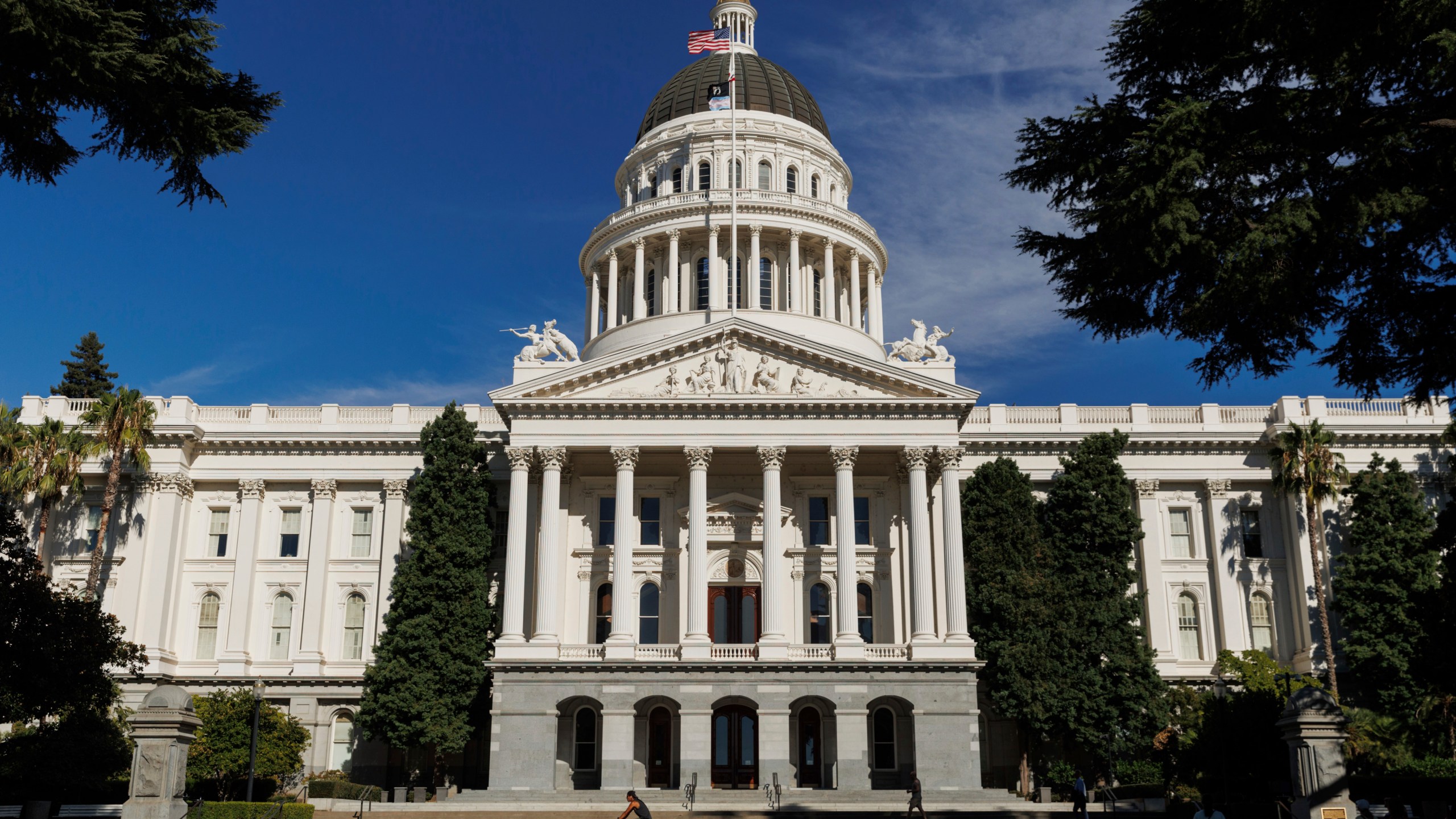 FILE - People walk around the California State Capitol, Aug. 5, 2024, in Sacramento, Calif. (AP Photo/Juliana Yamada, File)