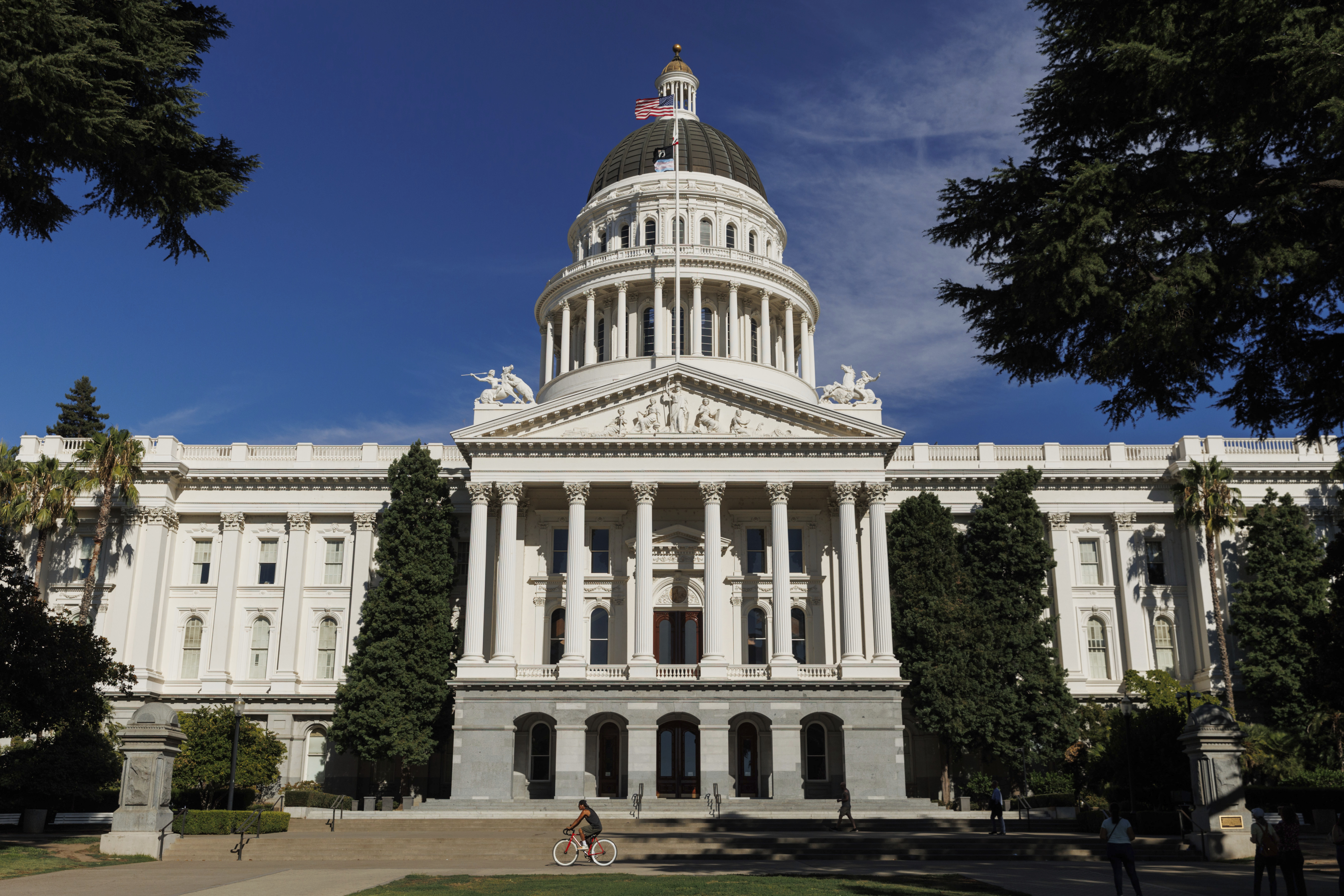 FILE - People walk around the California State Capitol, Aug. 5, 2024, in Sacramento, Calif. (AP Photo/Juliana Yamada, File)