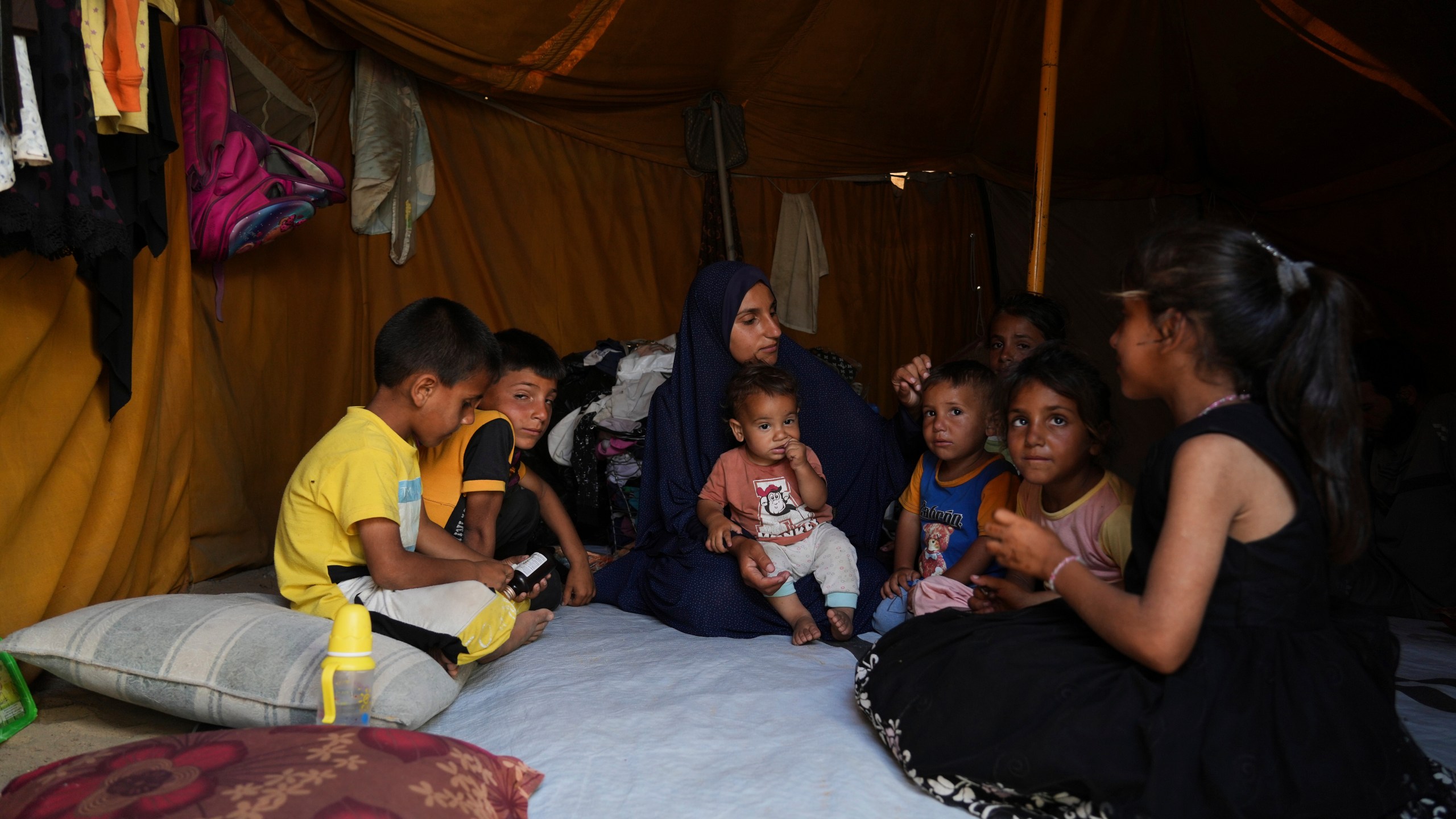 Maryam Abu Shaar, 29, sits with her children inside their tent at a camp for displaced Palestinians in Mawasi Khan Younis, Gaza Strip, on the first day of Eid al-Adha, Friday, June 6, 2025. (AP Photo/Abdel Kareem Hana)