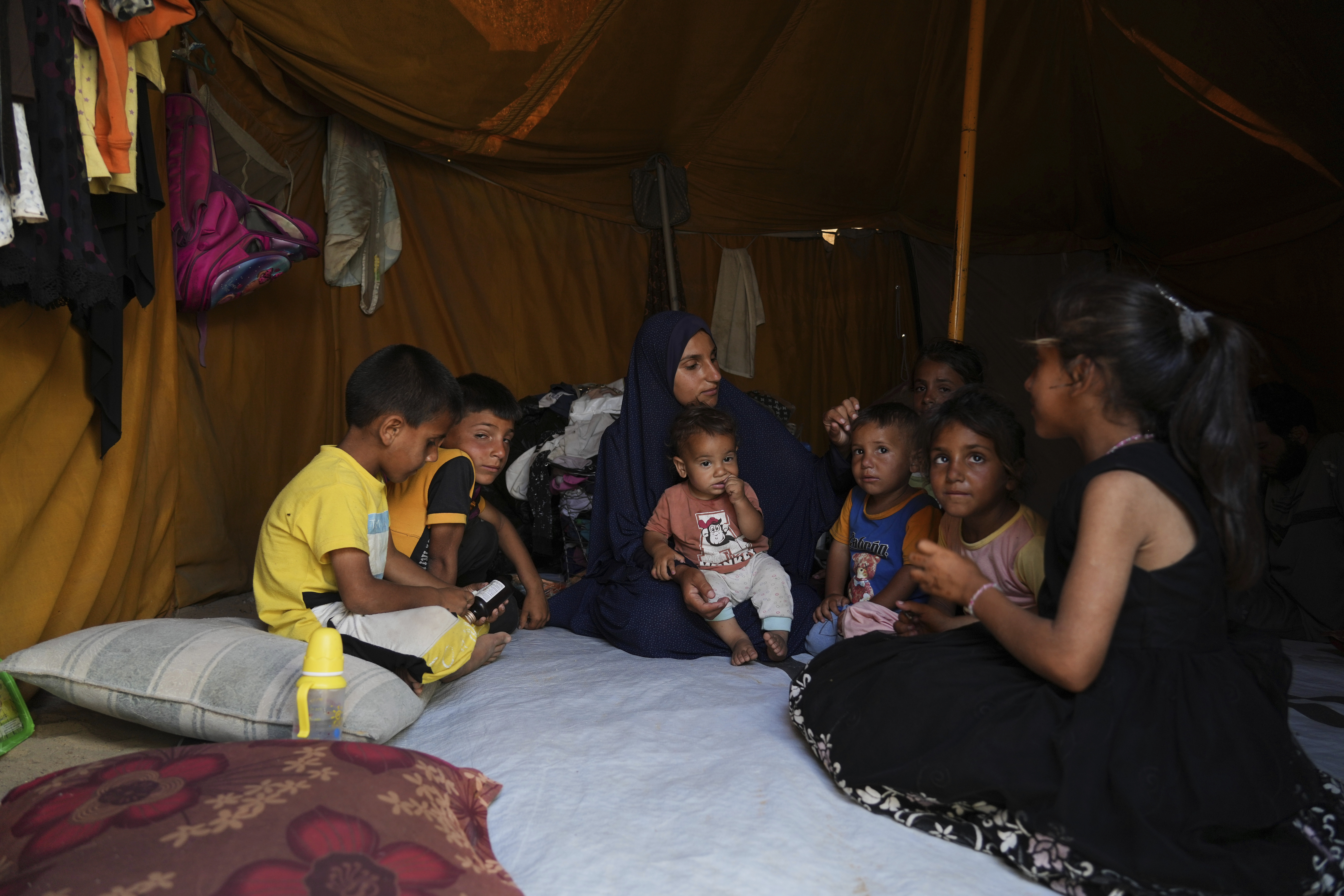 Maryam Abu Shaar, 29, sits with her children inside their tent at a camp for displaced Palestinians in Mawasi Khan Younis, Gaza Strip, on the first day of Eid al-Adha, Friday, June 6, 2025. (AP Photo/Abdel Kareem Hana)
