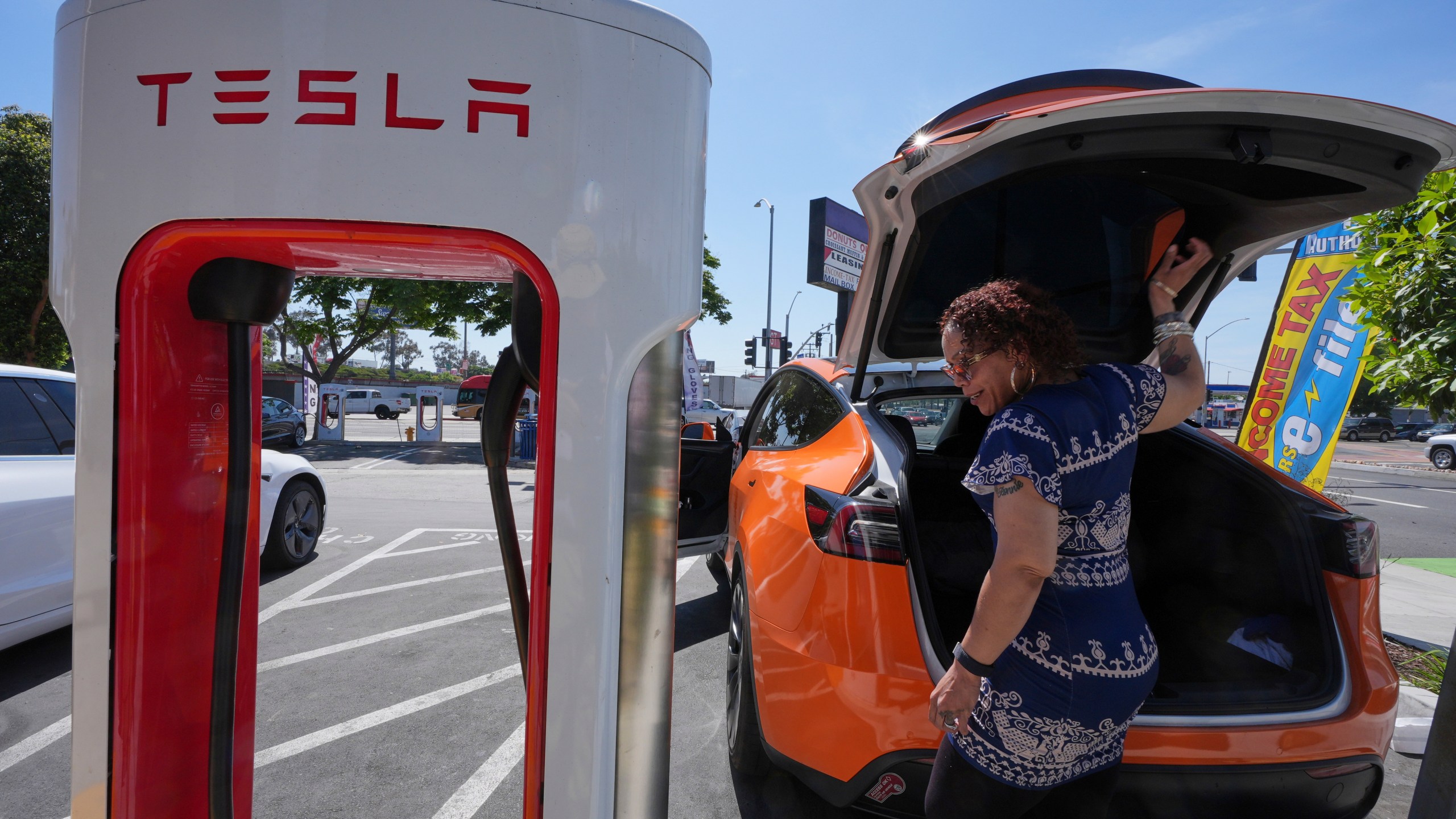 Janelle Lowe prepares to charge her electric vehicle at a charging station Thursday, May 22, 2025, in Long Beach, Calif. (AP Photo/Damian Dovarganes)