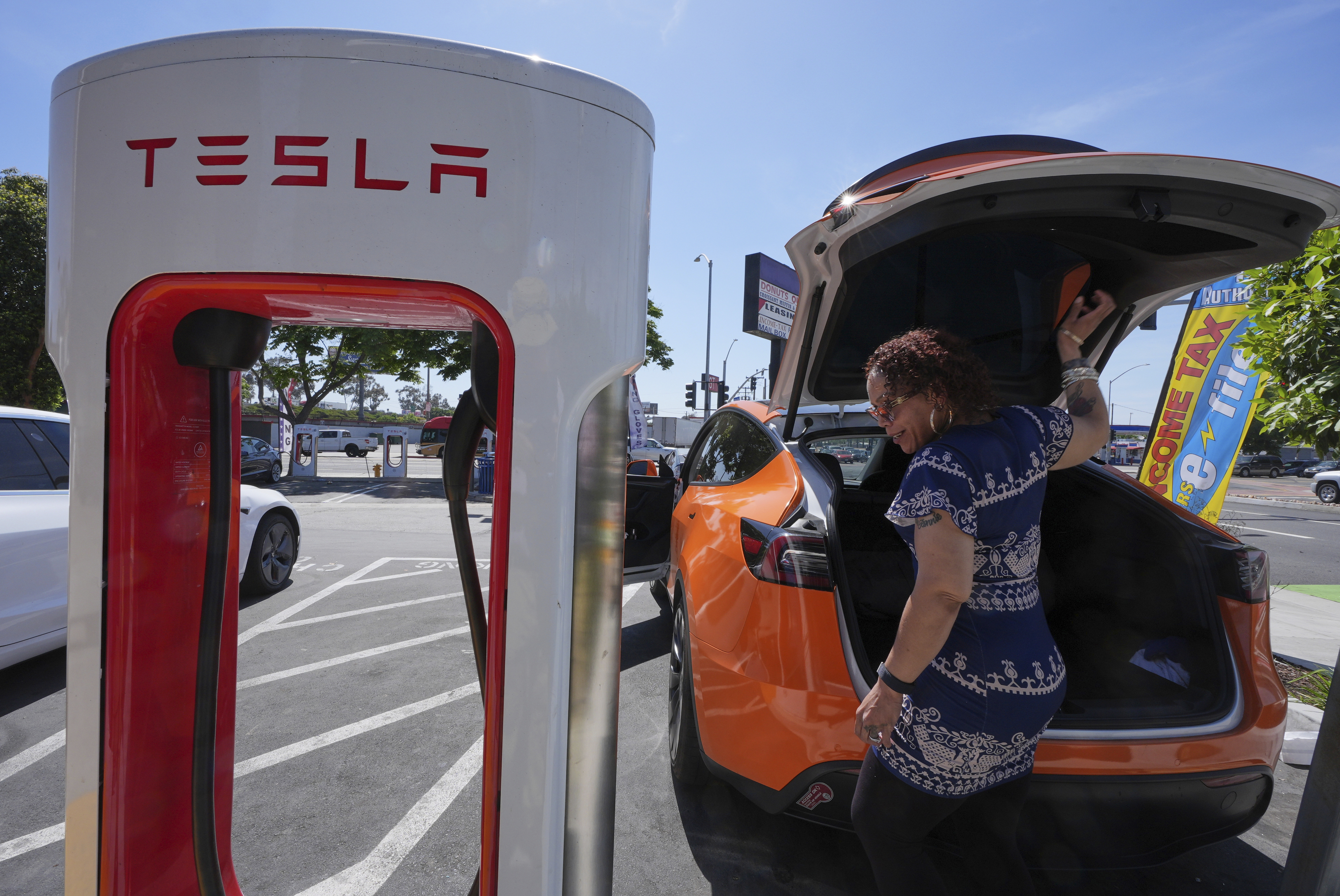 Janelle Lowe prepares to charge her electric vehicle at a charging station Thursday, May 22, 2025, in Long Beach, Calif. (AP Photo/Damian Dovarganes)