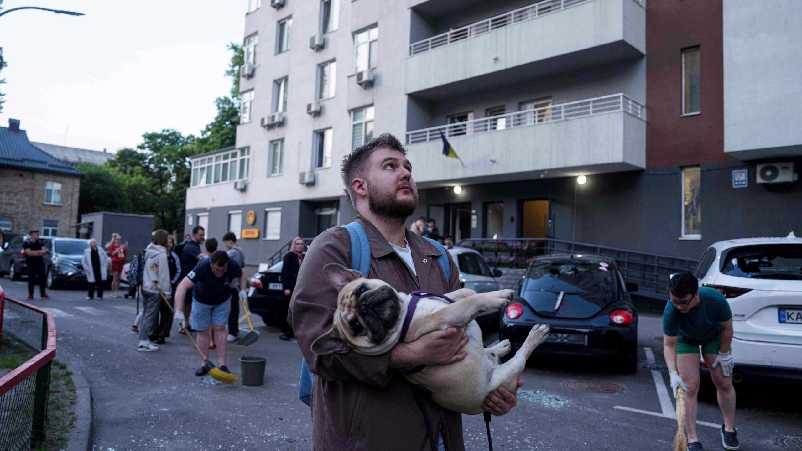 A man carries his dog in front of a residential multi-storey building damaged after a Russian drone strike on Kyiv, Ukraine, on Friday, June 6, 2025. (AP Photo/Evgeniy Maloletka)