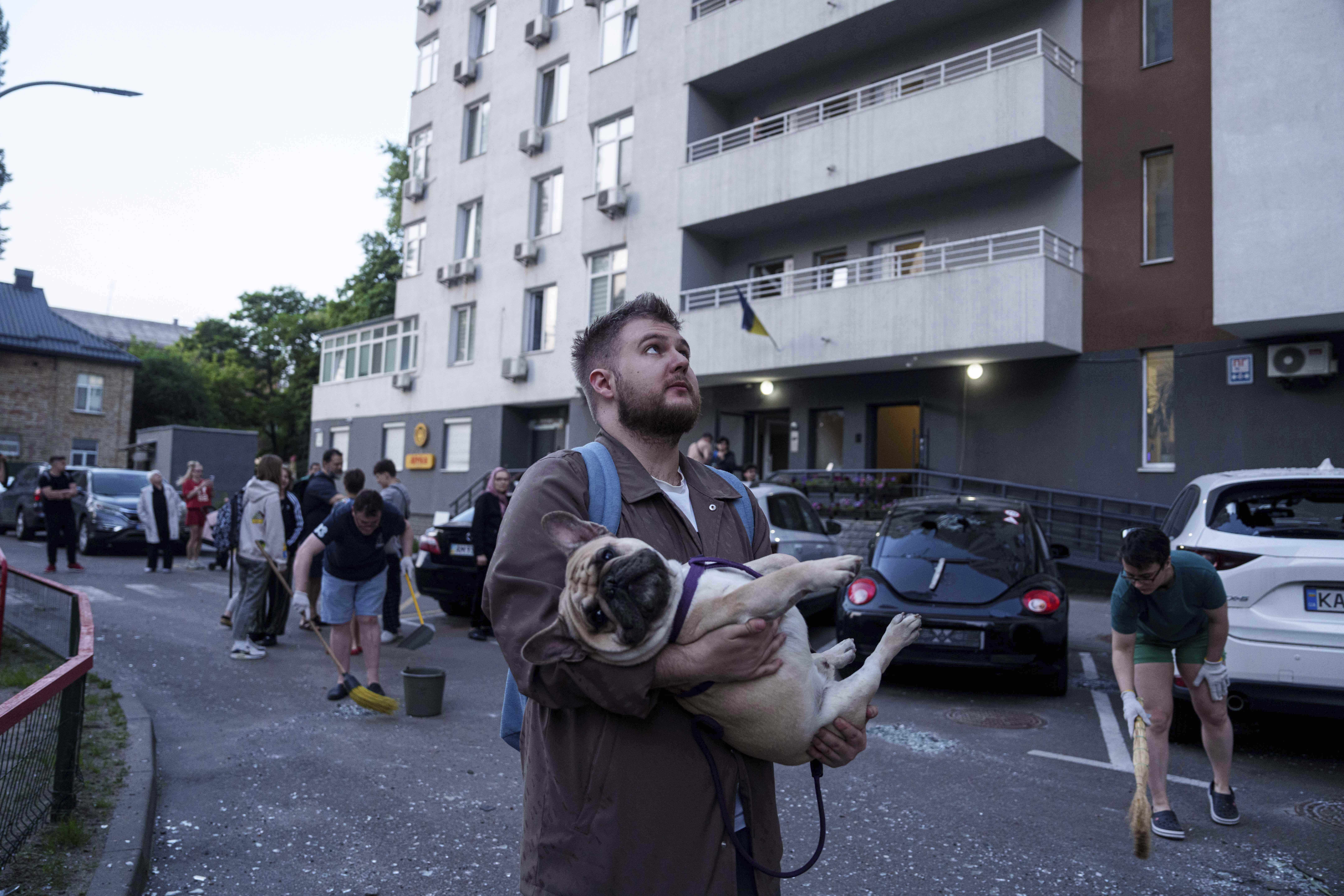 A man carries his dog in front of a residential multi-storey building damaged after a Russian drone strike on Kyiv, Ukraine, on Friday, June 6, 2025. (AP Photo/Evgeniy Maloletka)