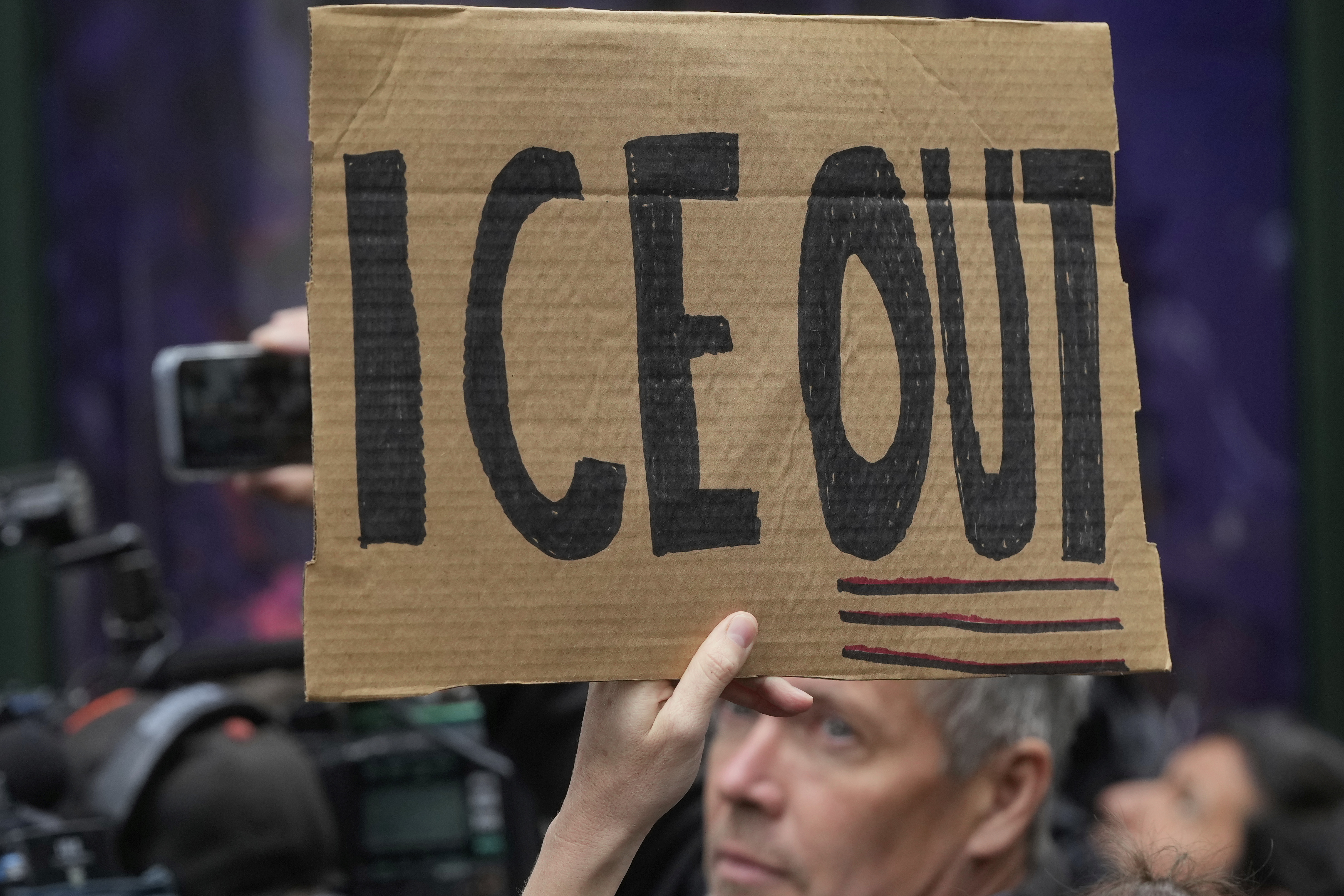 A person holds up a sign during a news conference and rally by immigrant justice organizations and advocates protesting ICE arrests in San Francisco, Wednesday, May 28, 2025. (AP Photo/Jeff Chiu)