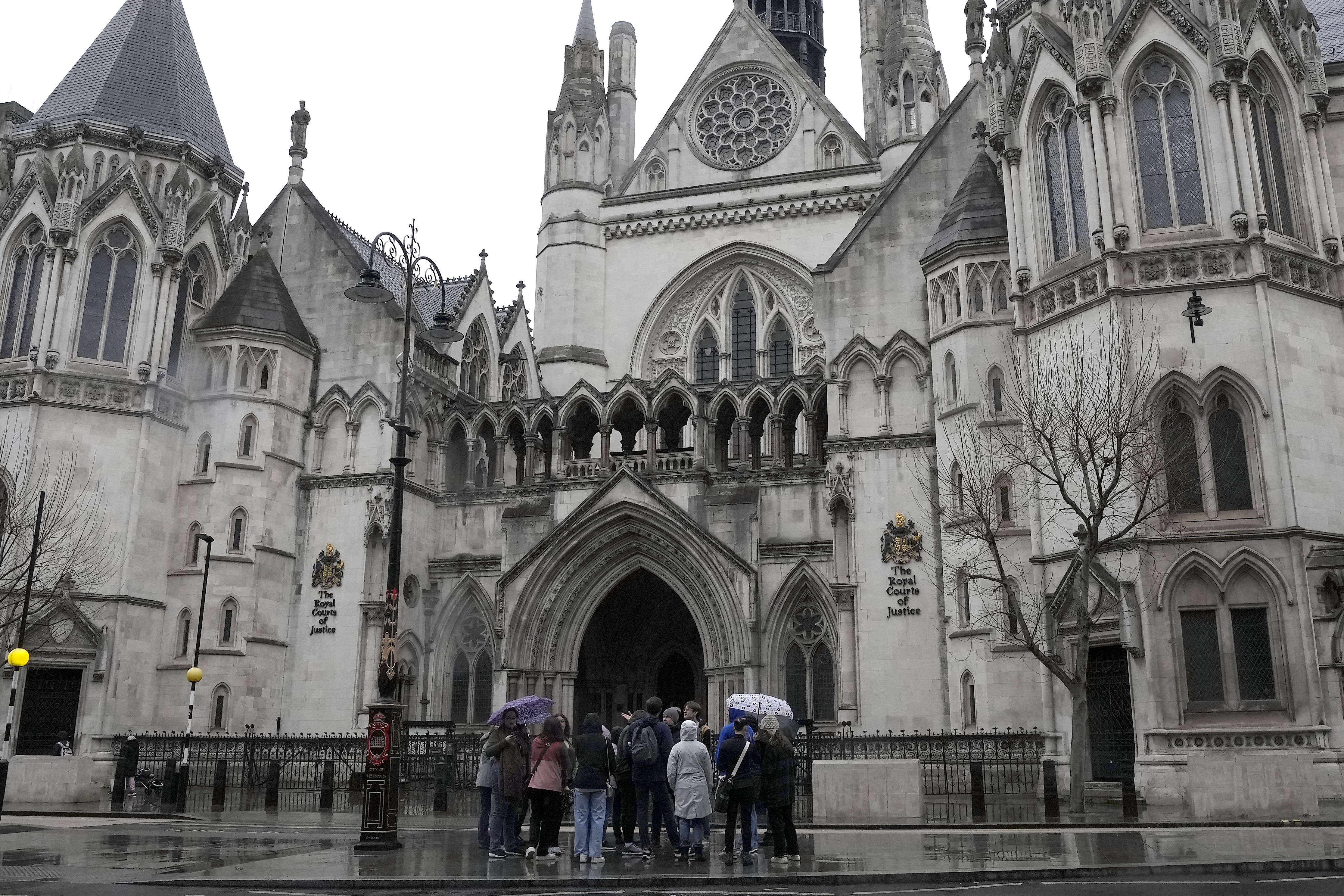 FILE - People stand outside the Royal Court of Justice in London, Friday, March 17, 2023. (AP Photo/Frank Augstein, File)