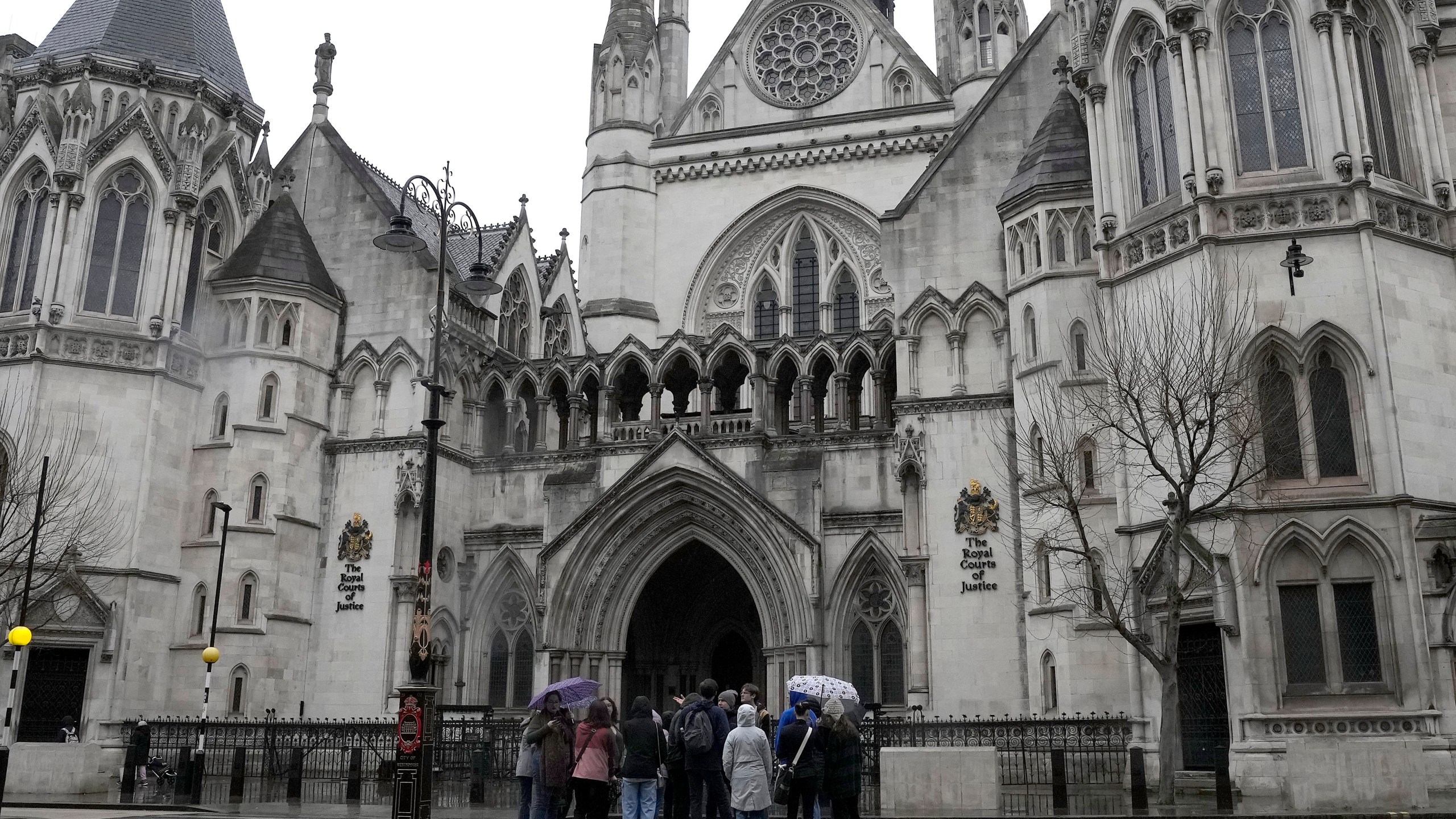 FILE - People stand outside the Royal Court of Justice in London, Friday, March 17, 2023. (AP Photo/Frank Augstein, File)