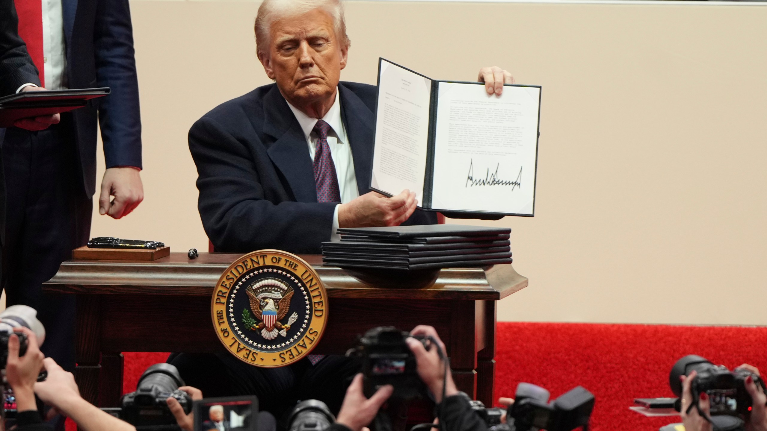 FILE - President Donald Trump holds up an executive order after signing it at an indoor Presidential Inauguration parade event in Washington, Jan. 20, 2025. (AP Photo/Matt Rourke, File)