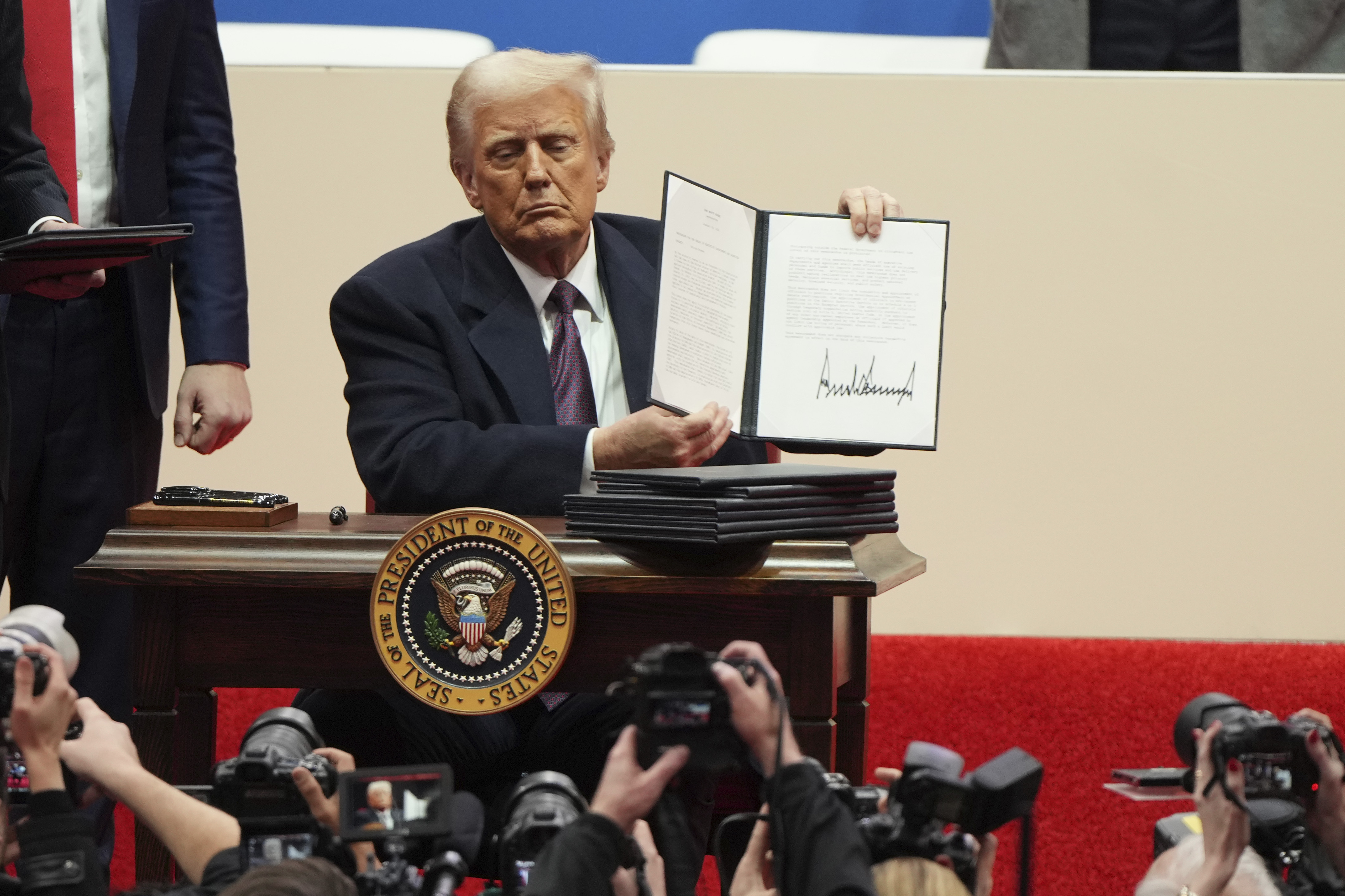 FILE - President Donald Trump holds up an executive order after signing it at an indoor Presidential Inauguration parade event in Washington, Jan. 20, 2025. (AP Photo/Matt Rourke, File)