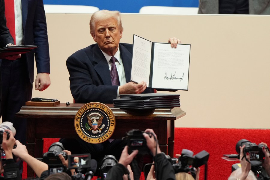 FILE - President Donald Trump holds up an executive order after signing it at an indoor Presidential Inauguration parade event in Washington, Jan. 20, 2025. (AP Photo/Matt Rourke, File)