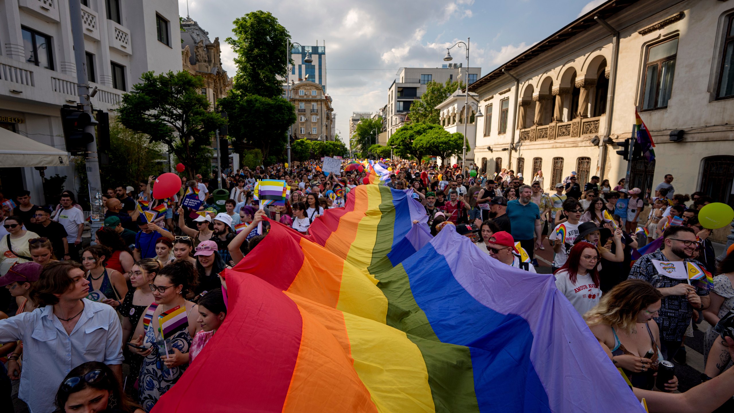 People hold a rainbow flag banner during the gay pride parade in Bucharest, Romania, Saturday, June 7, 2025. (AP Photo/Andreea Alexandru)