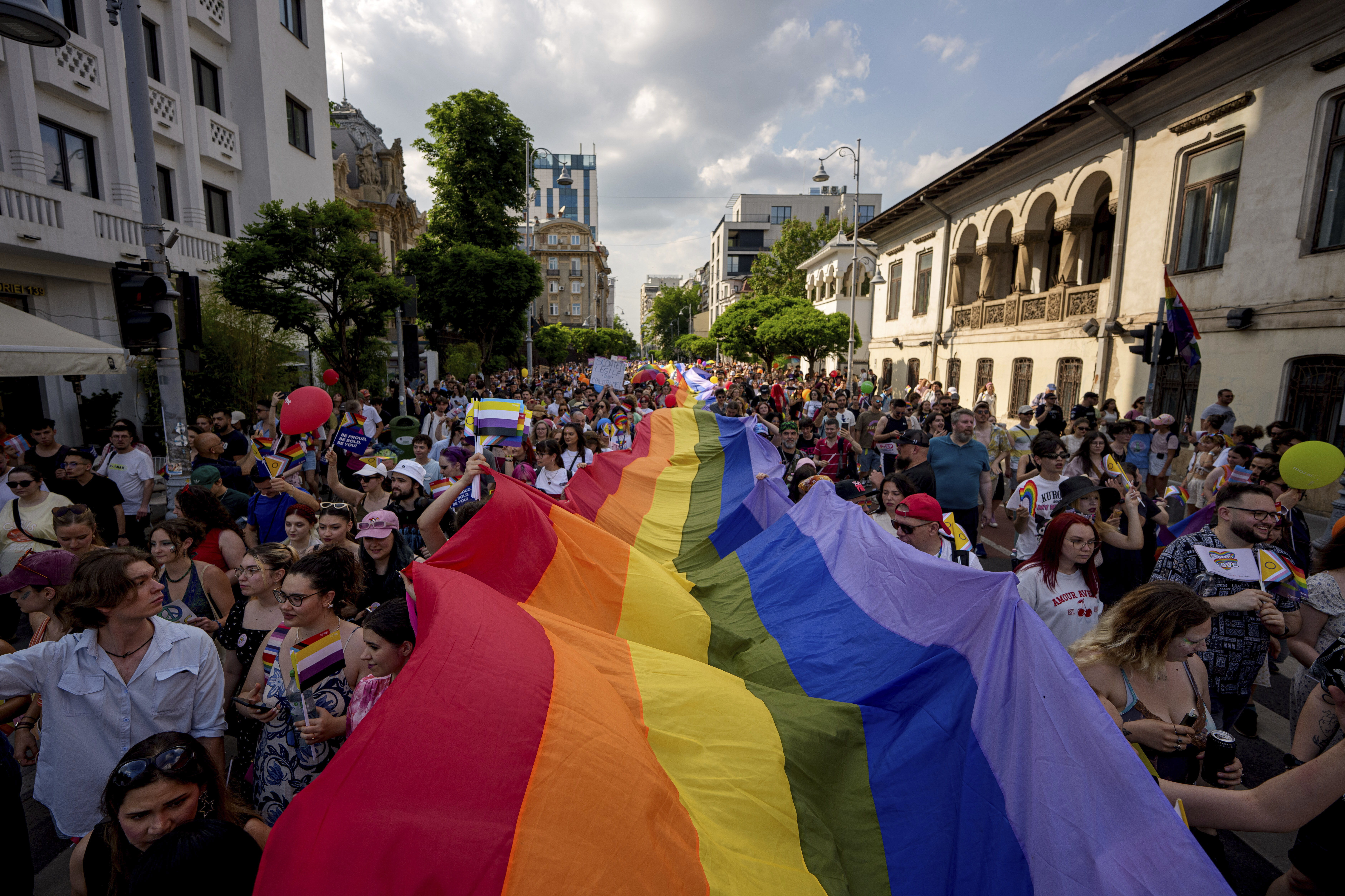 People hold a rainbow flag banner during the gay pride parade in Bucharest, Romania, Saturday, June 7, 2025. (AP Photo/Andreea Alexandru)