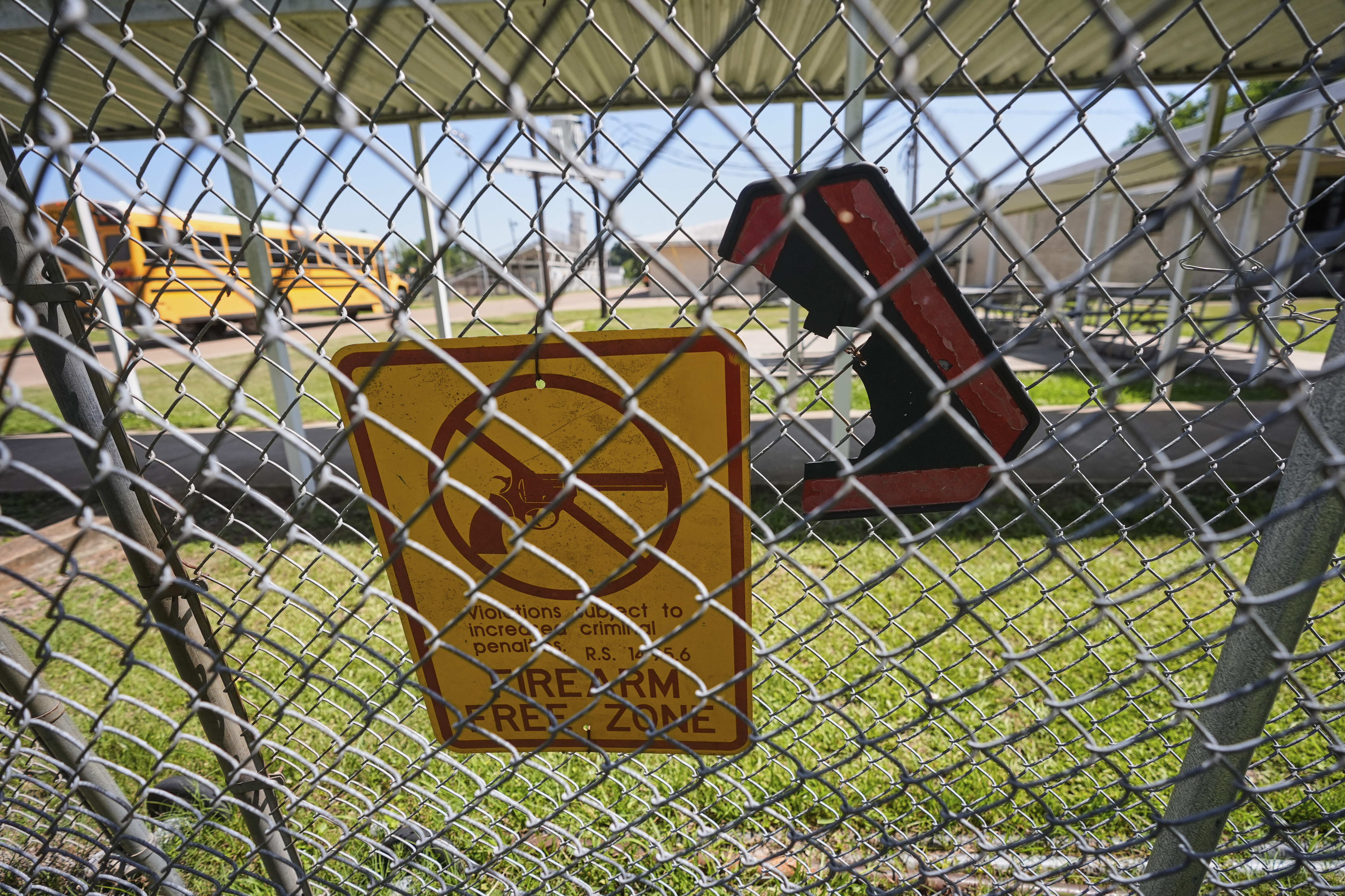 A signs warns of firearms on a fence at a gate for Ferriday High School in Ferriday, La., Thursday, May 22, 2025. (AP Photo/Gerald Herbert)